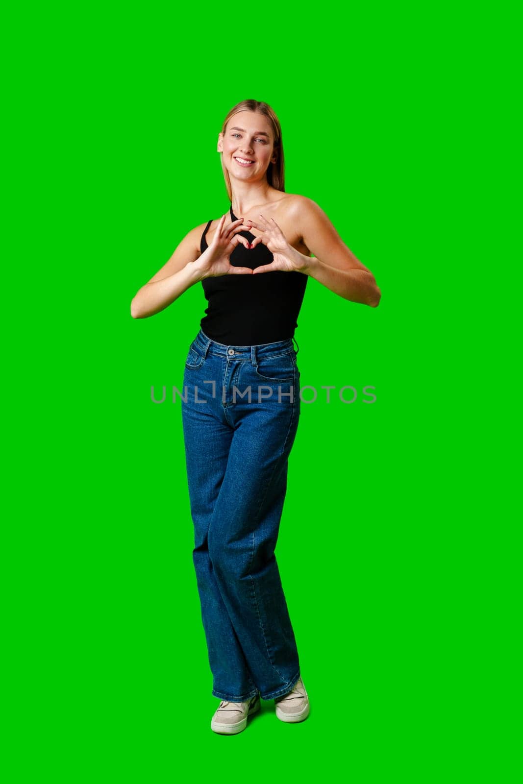 Young Woman Making Heart With Hands on green background in studio