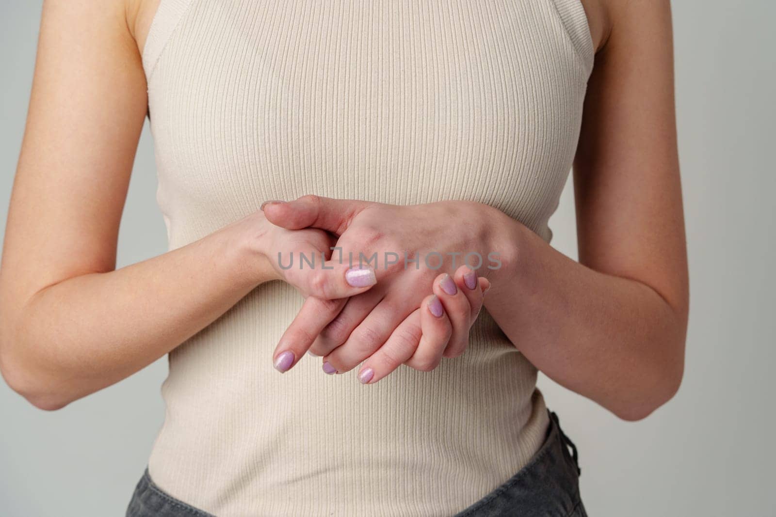 Female body in beige top on gray background close up