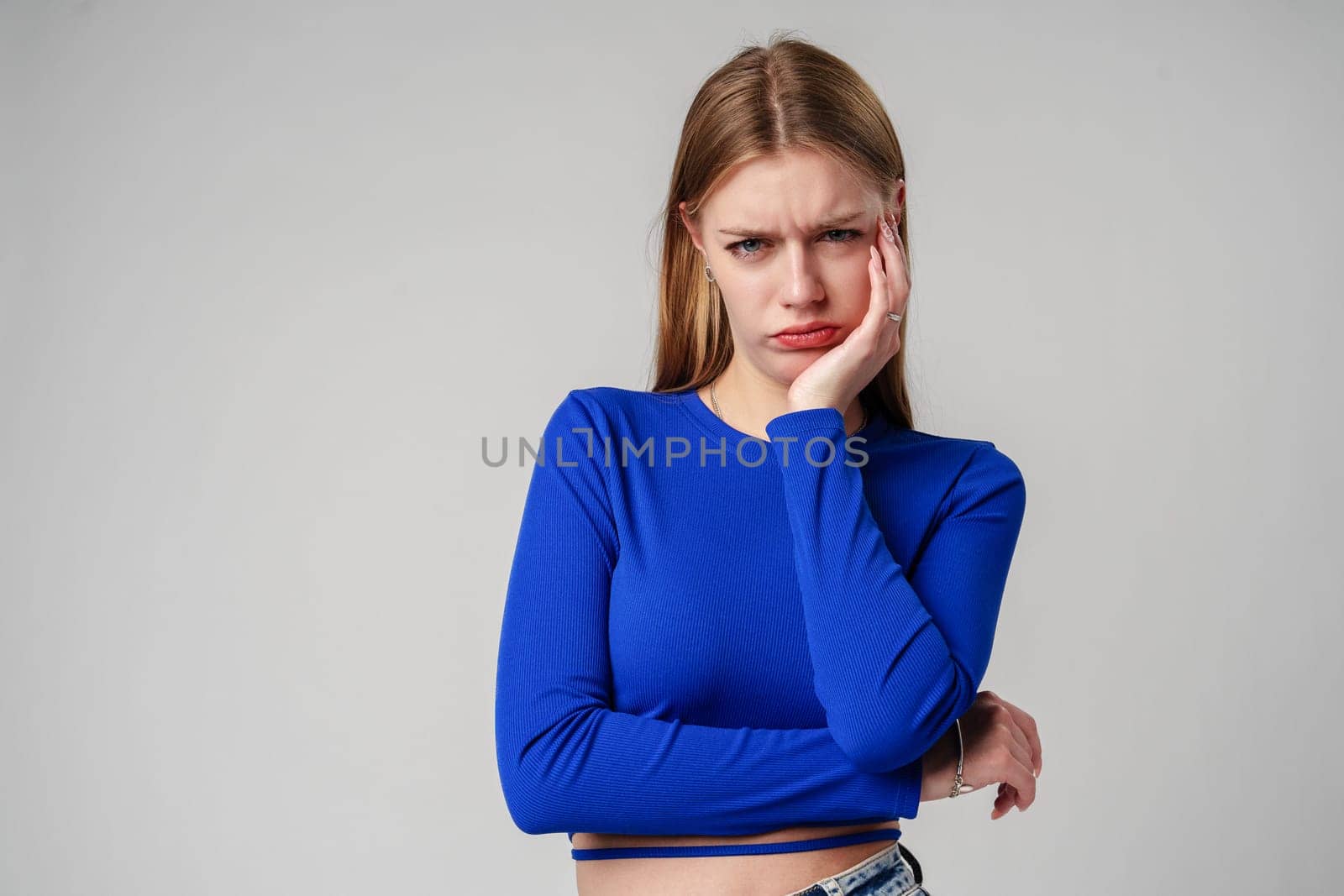 Young Woman In Black Shirt Expressing Discontent Against Grey Background close up