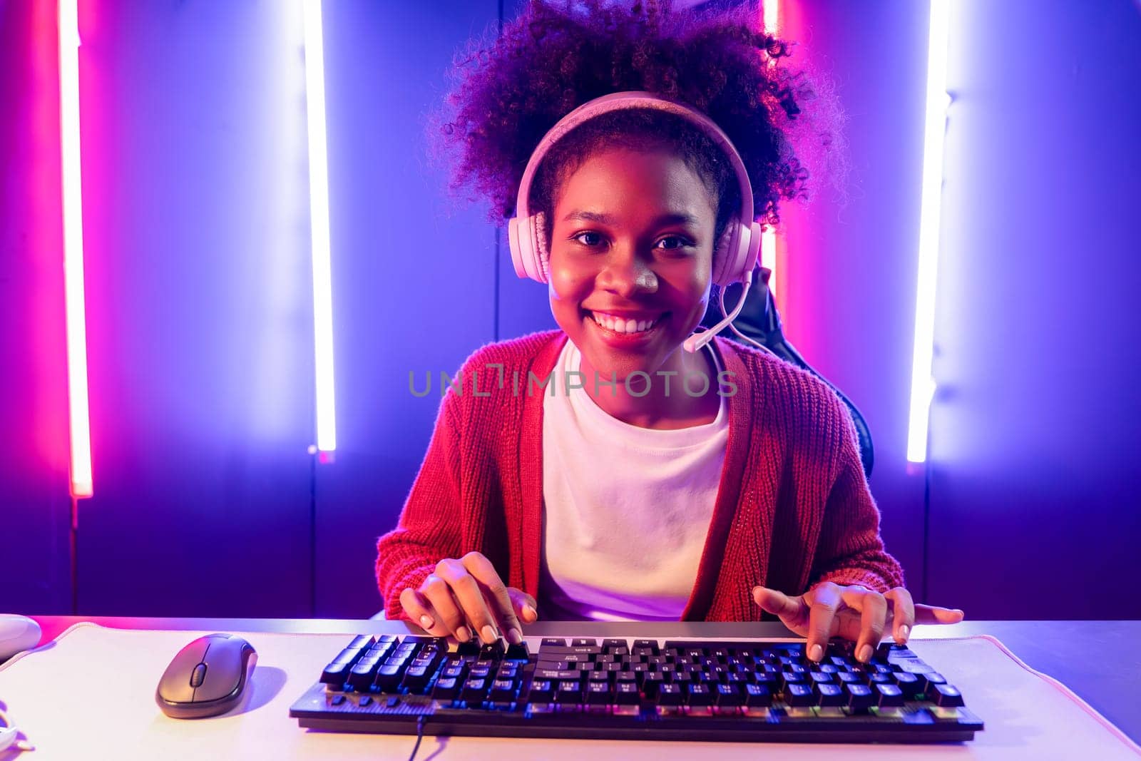 Gaming streamer, African girl playing online fighting with Esport skilled team wearing headphones in neon color lighting room. Talking other players planing strategies to win competitors. Tastemaker.