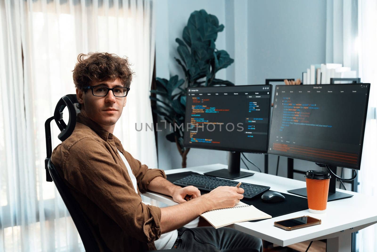 IT developer in online software development information looking at camera surrounded coding pc screens at side view, working on design new program for latest version at modern home office. Gusher.