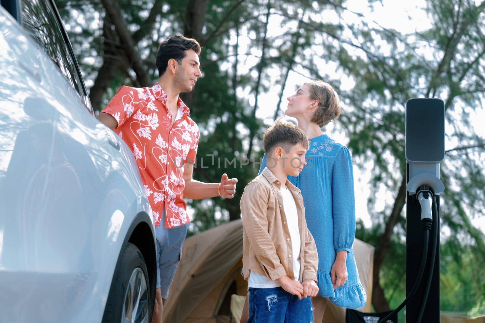 Lovely family recharge EV car with EV charging station in campsite. Perpetual by biancoblue