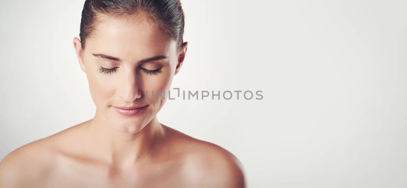 Woman, skincare and calm in studio for beauty with soft, smooth and clear skin with wellness. Girl, isolated and white background for cosmetics or dermatology, self care and happiness with mockup by YuriArcurs