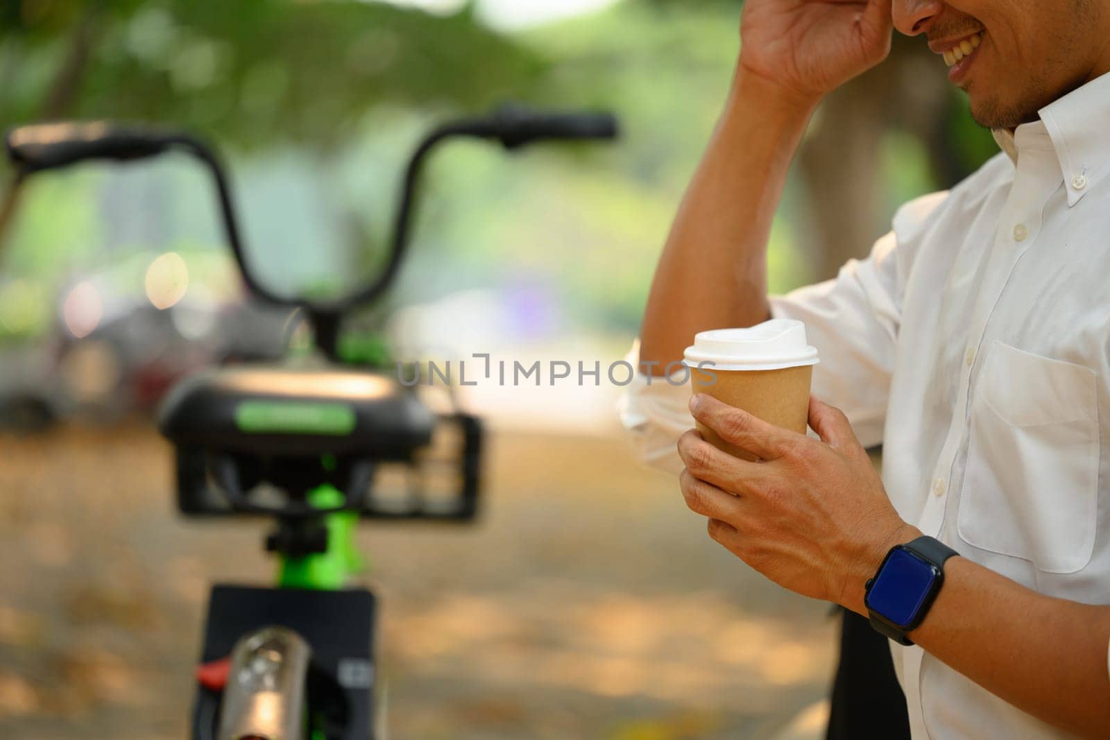 Cropped shot of relaxed businessman sitting on the park bench and drinking coffee by prathanchorruangsak