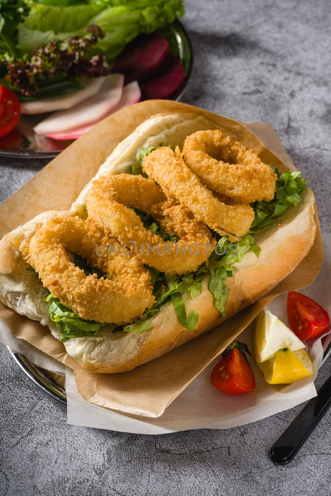 Deep fried squid in bread with greens on the side. Squid sandwich