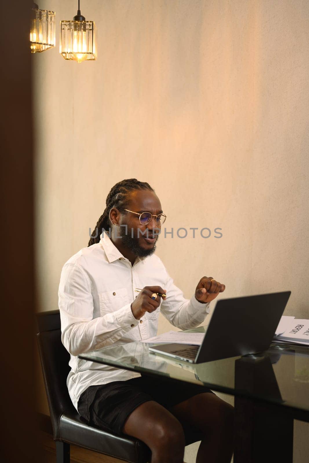 Handsome African American man entrepreneur having video call on laptop at home by prathanchorruangsak