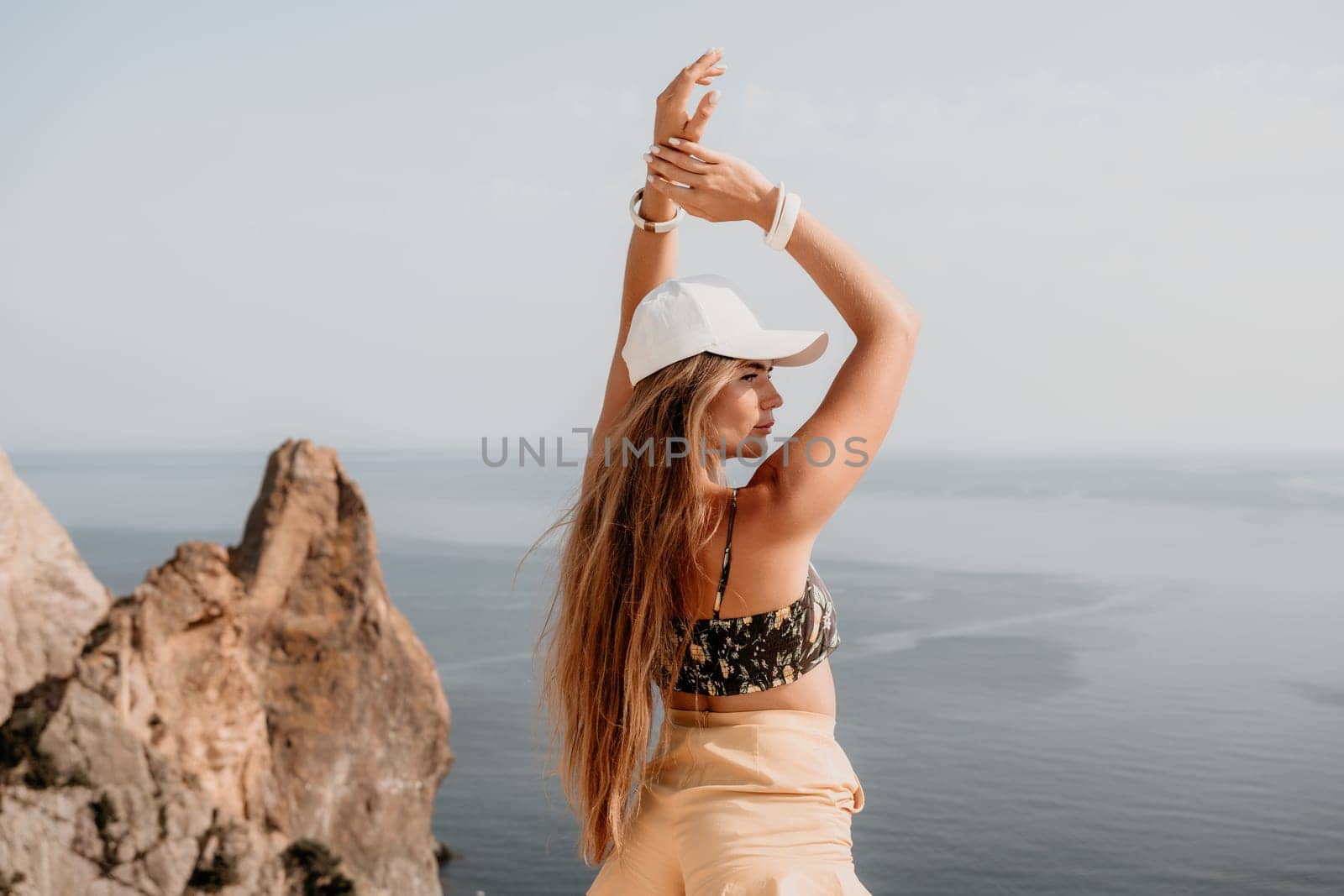 Woman travel sea. Happy tourist enjoy taking picture outdoors for memories. Woman traveler looks at the edge of the cliff on the sea bay of mountains, sharing travel adventure journey by panophotograph