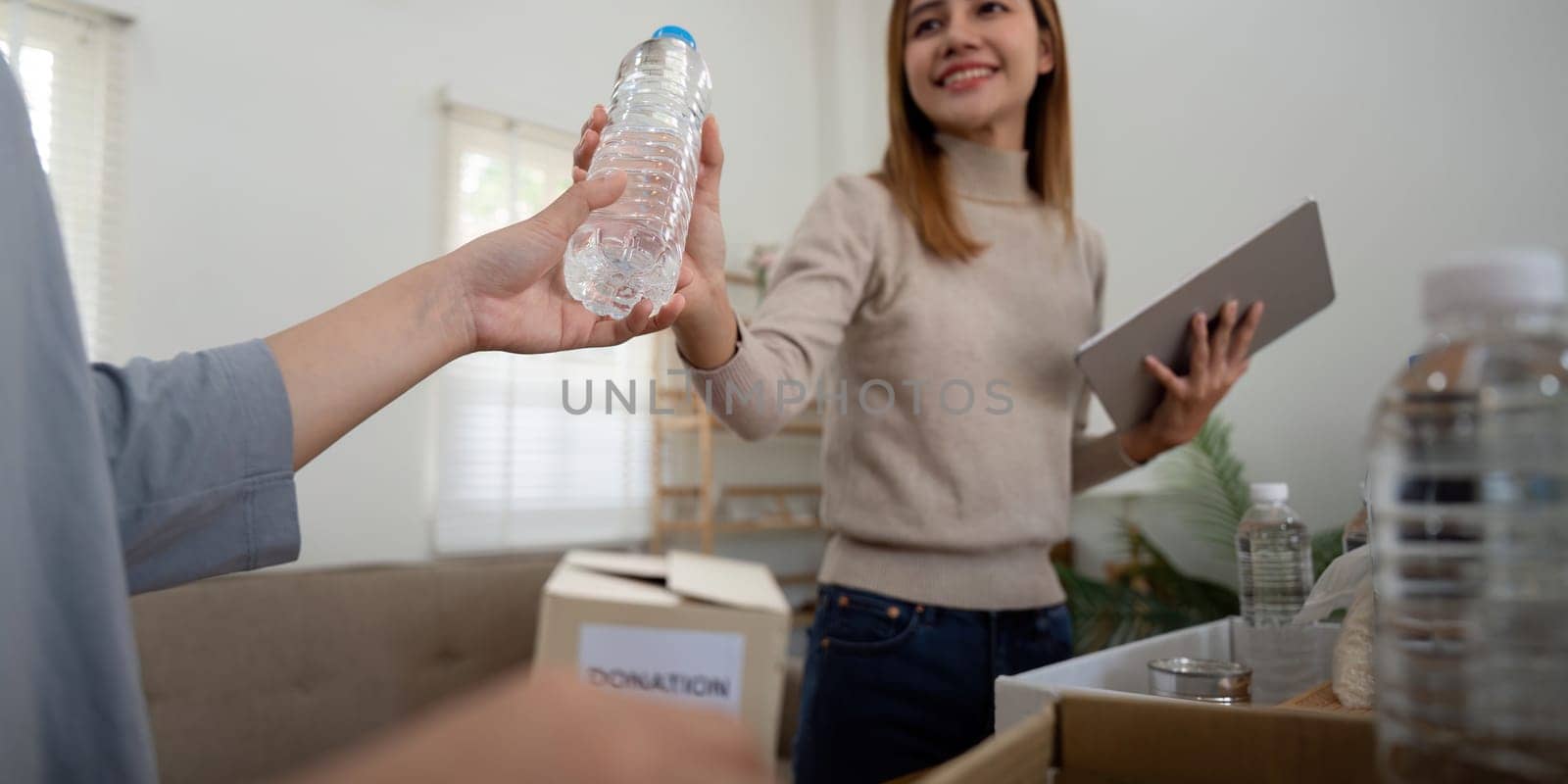 Donation and two woman volunteer asian of happy packing food in box at home. Charity by nateemee