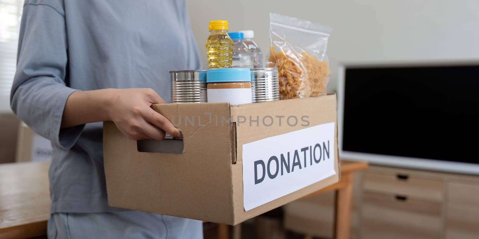 Woman volunteer holding food donation box at home.