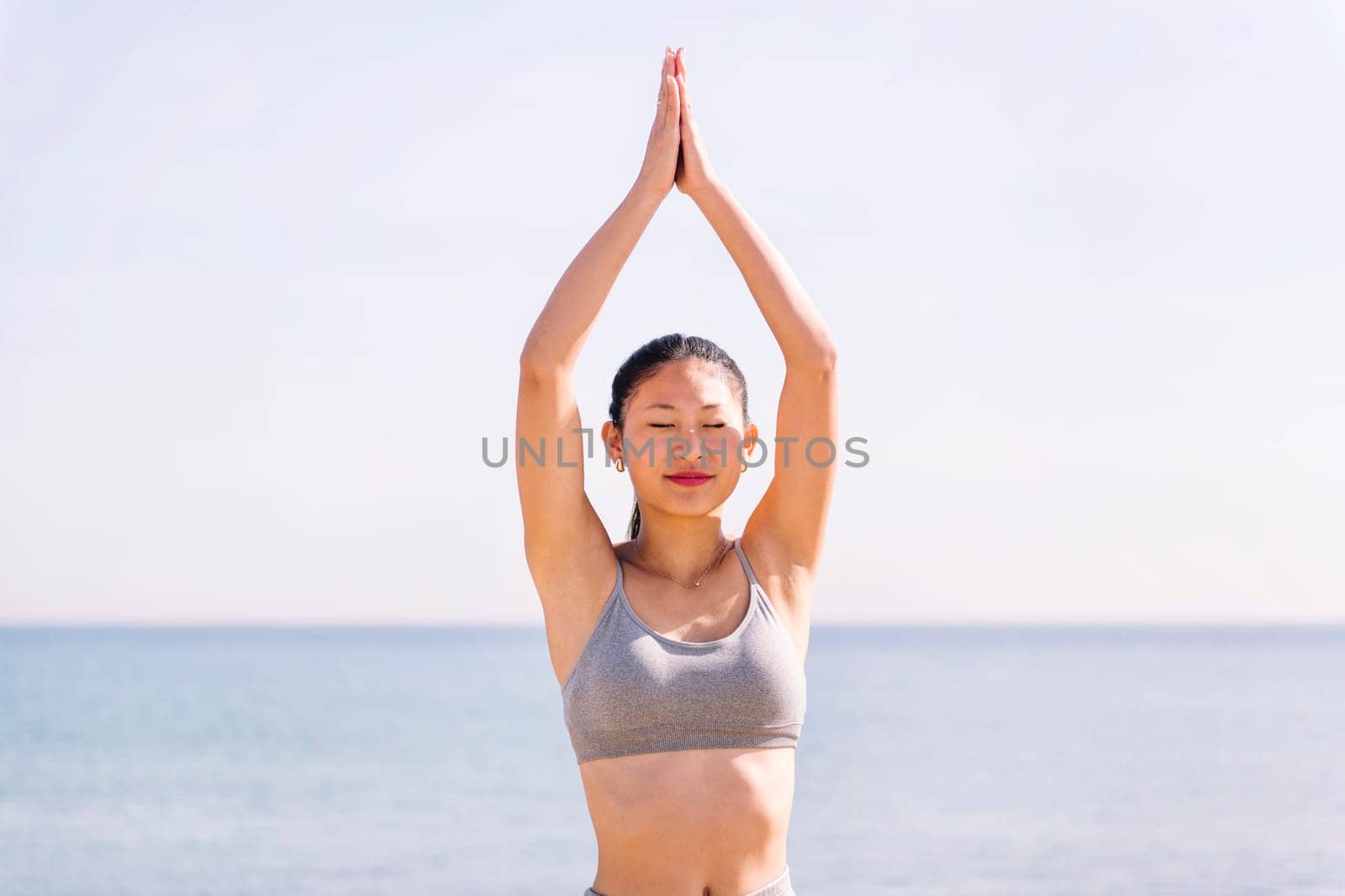 young asian woman doing yoga position at beach by raulmelldo