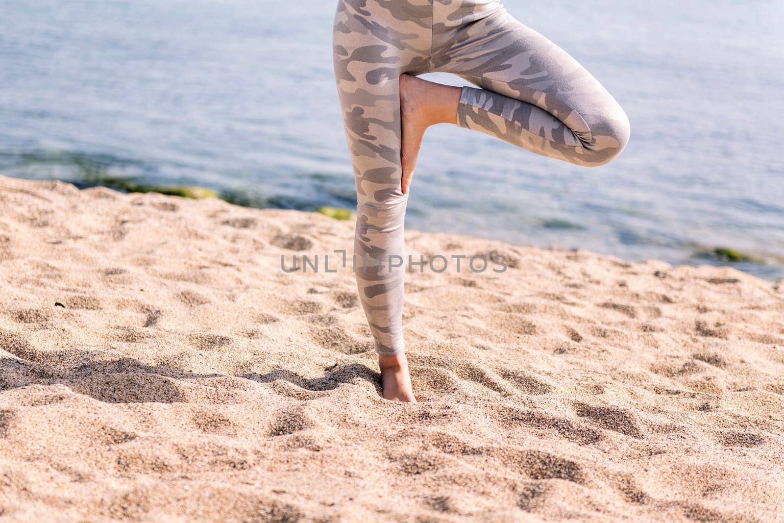 close up detail of an unrecognizable woman doing yoga position at beach, concept of mental relaxation and healthy lifestyle