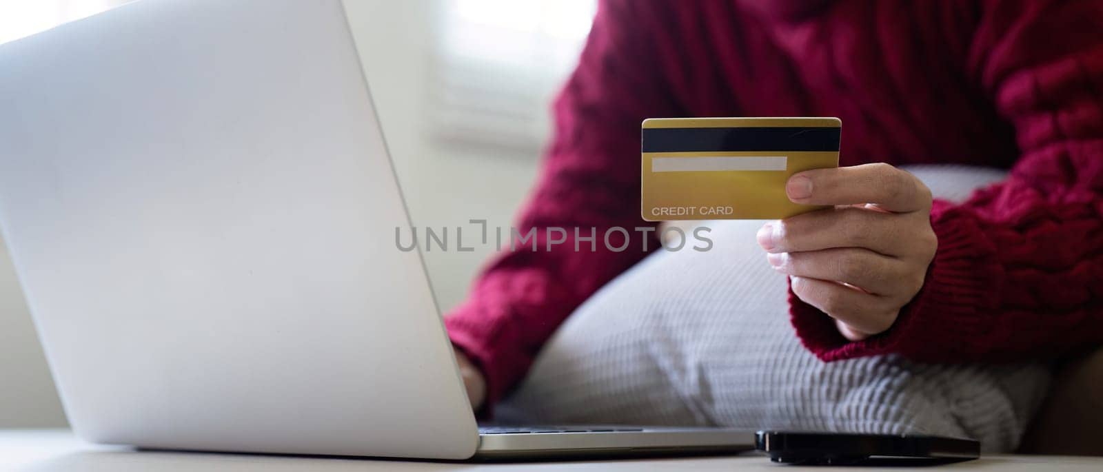 Young Asian woman hands holding credit card and using laptop for internet purchase. Online shopping, Online payment at home.