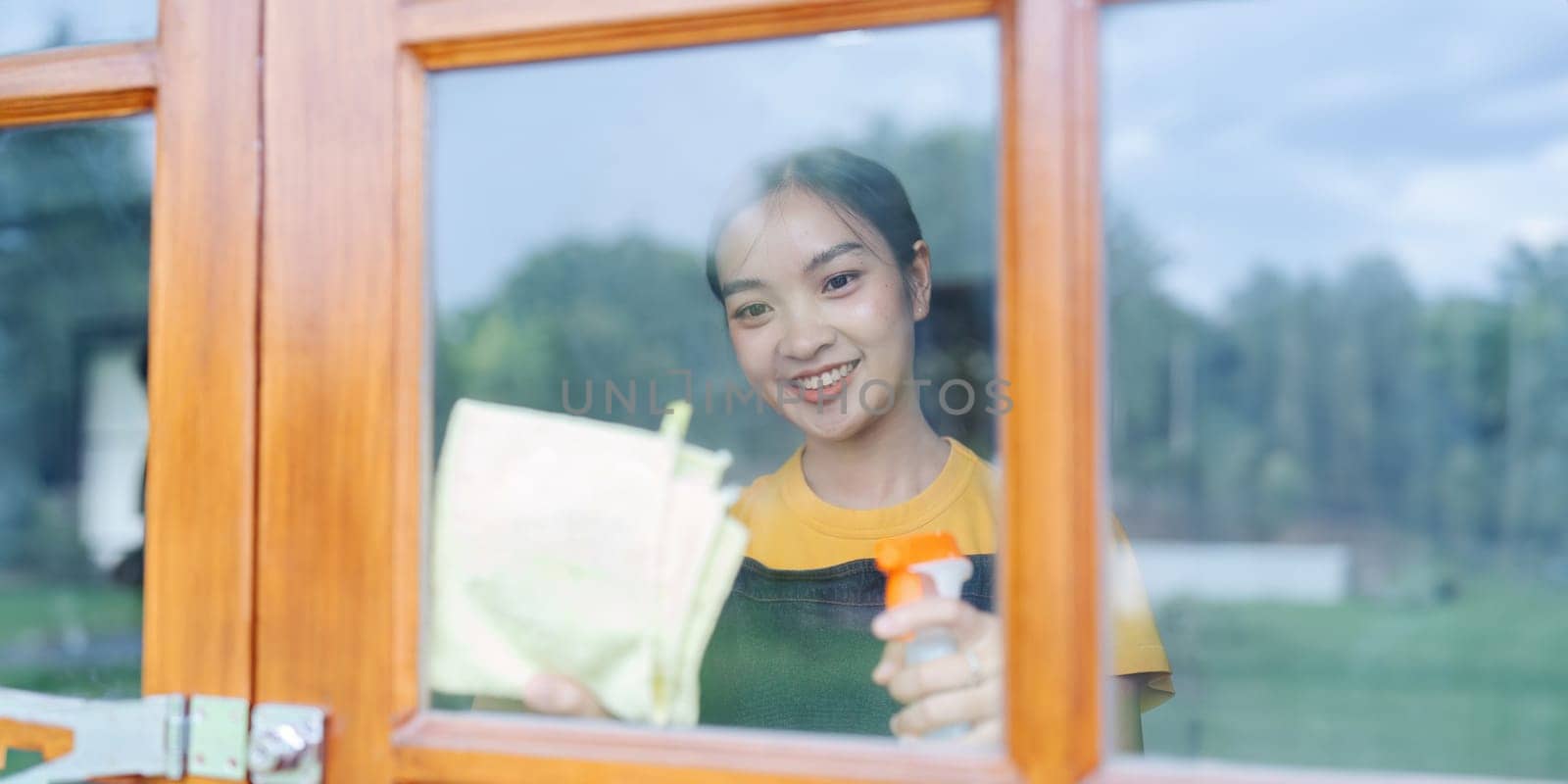 Woman doing household chores and wiping windows in the house on weekends by itchaznong