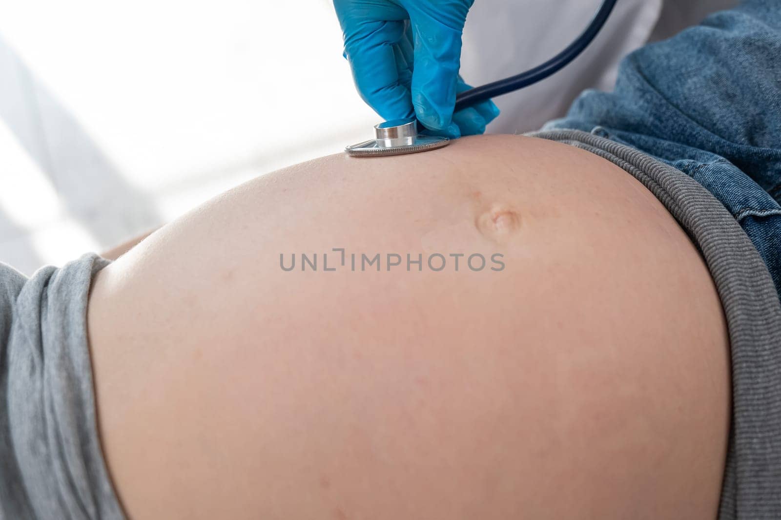 The doctor listens to the heartbeat of the baby of a pregnant woman