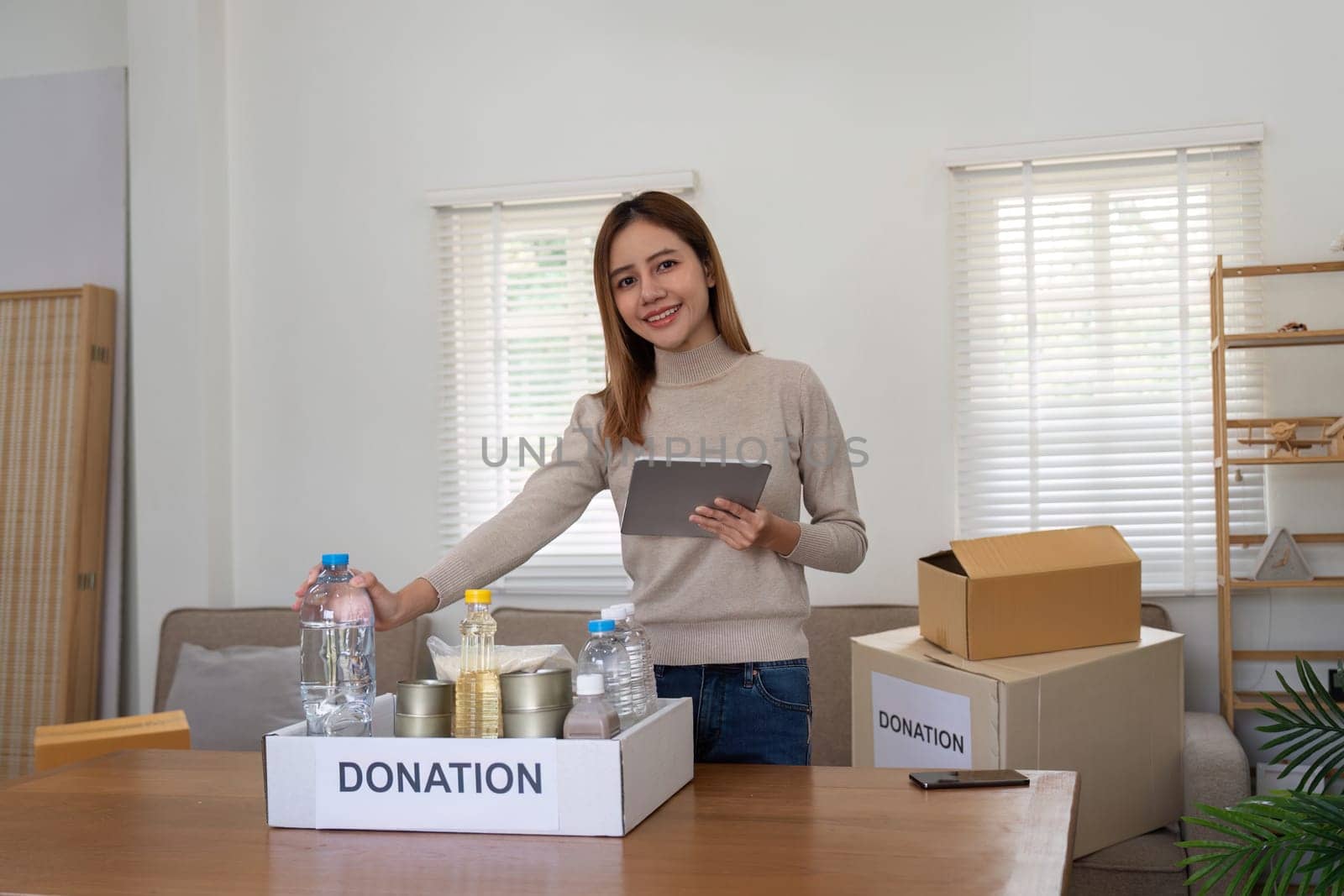 Volunteer woman asian pack donate food in cardboard box for people in need during by nateemee