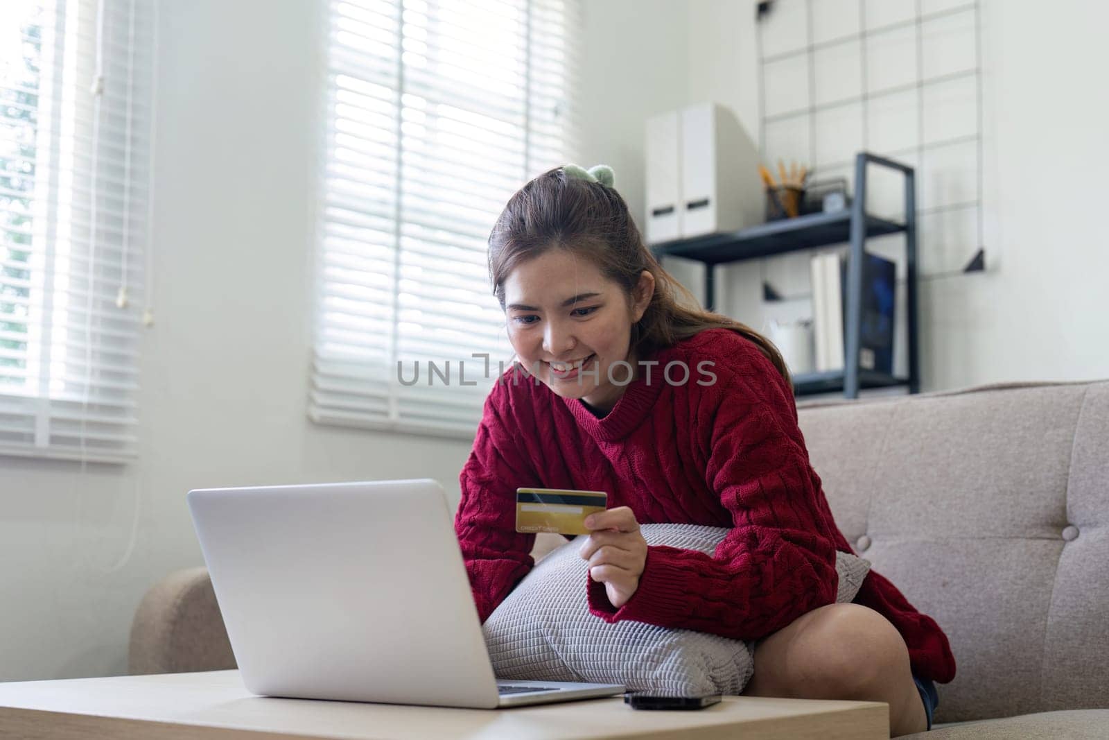 Young Asian woman hands holding credit card and using laptop for internet purchase. Online shopping, Online payment at home by nateemee