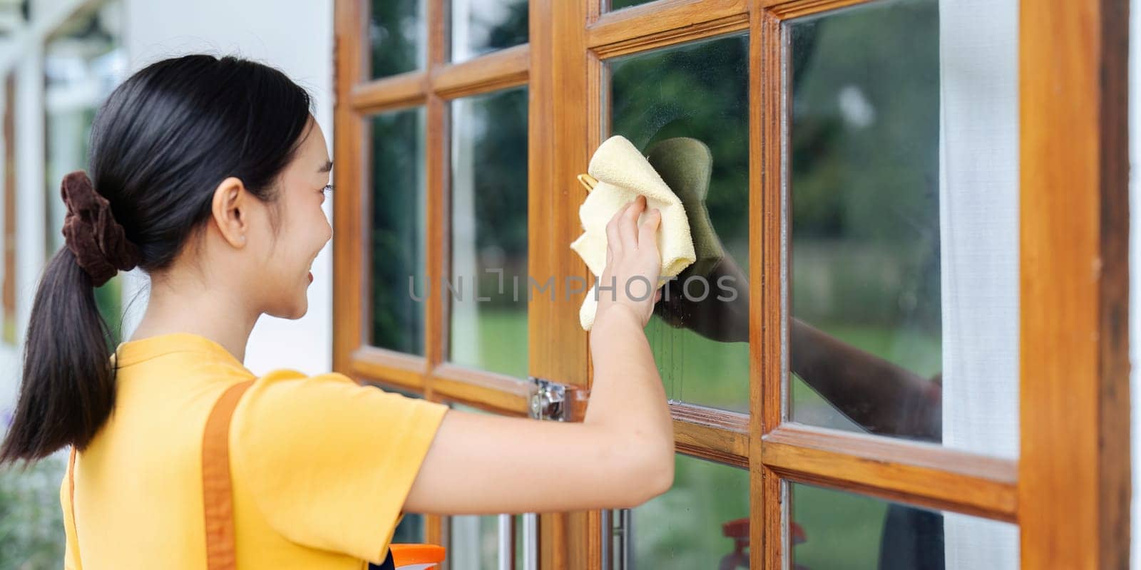 Woman doing household chores and wiping windows in the house on weekends.
