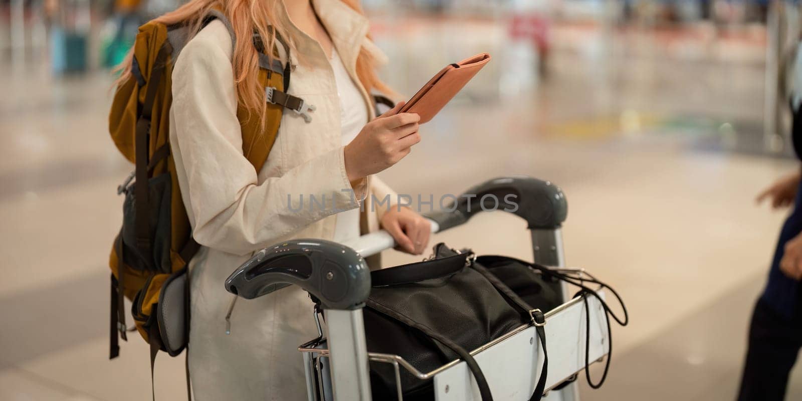 Hand of woman passenger holding passport with the flight in airport terminal.