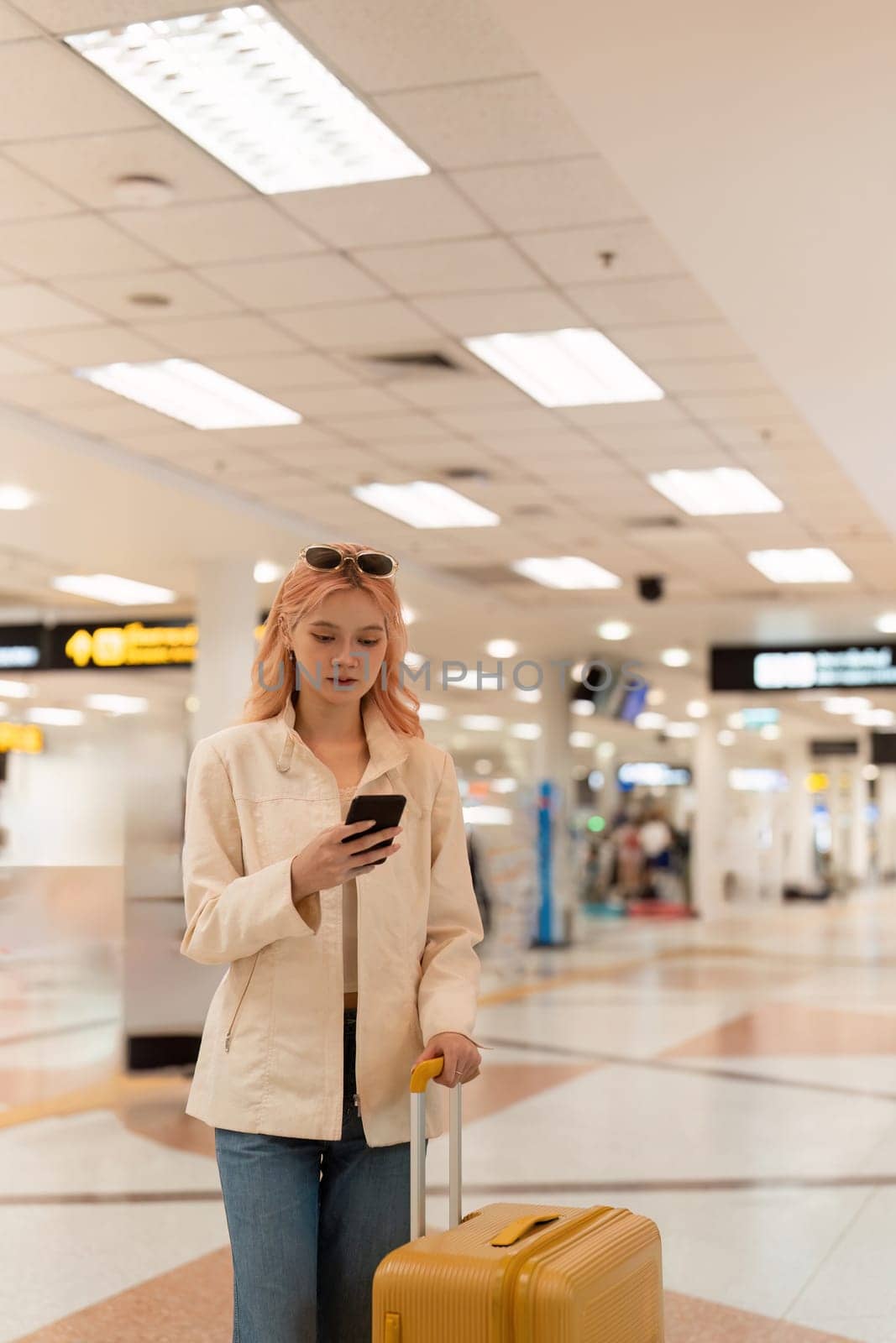 A woman asian walking in an airport. Mobile, suitcase and travel with a young female on an international trip for work or travel.