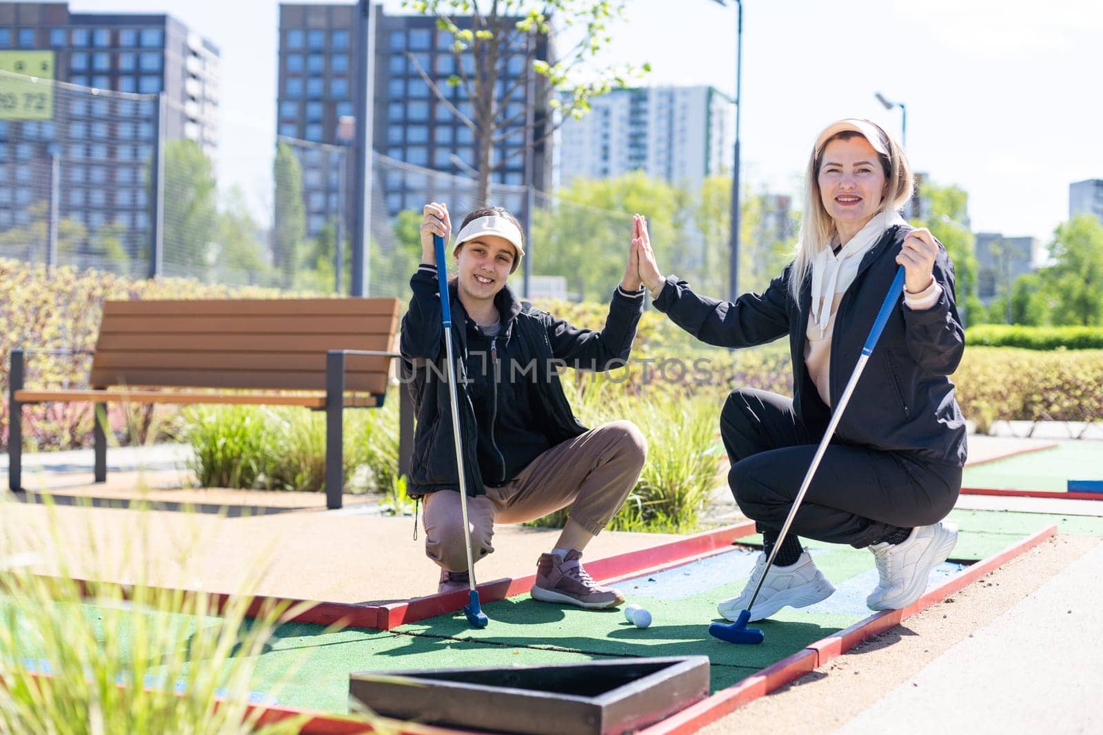 mother and daughter playing mini golf, children enjoying summer vacation. High quality photo