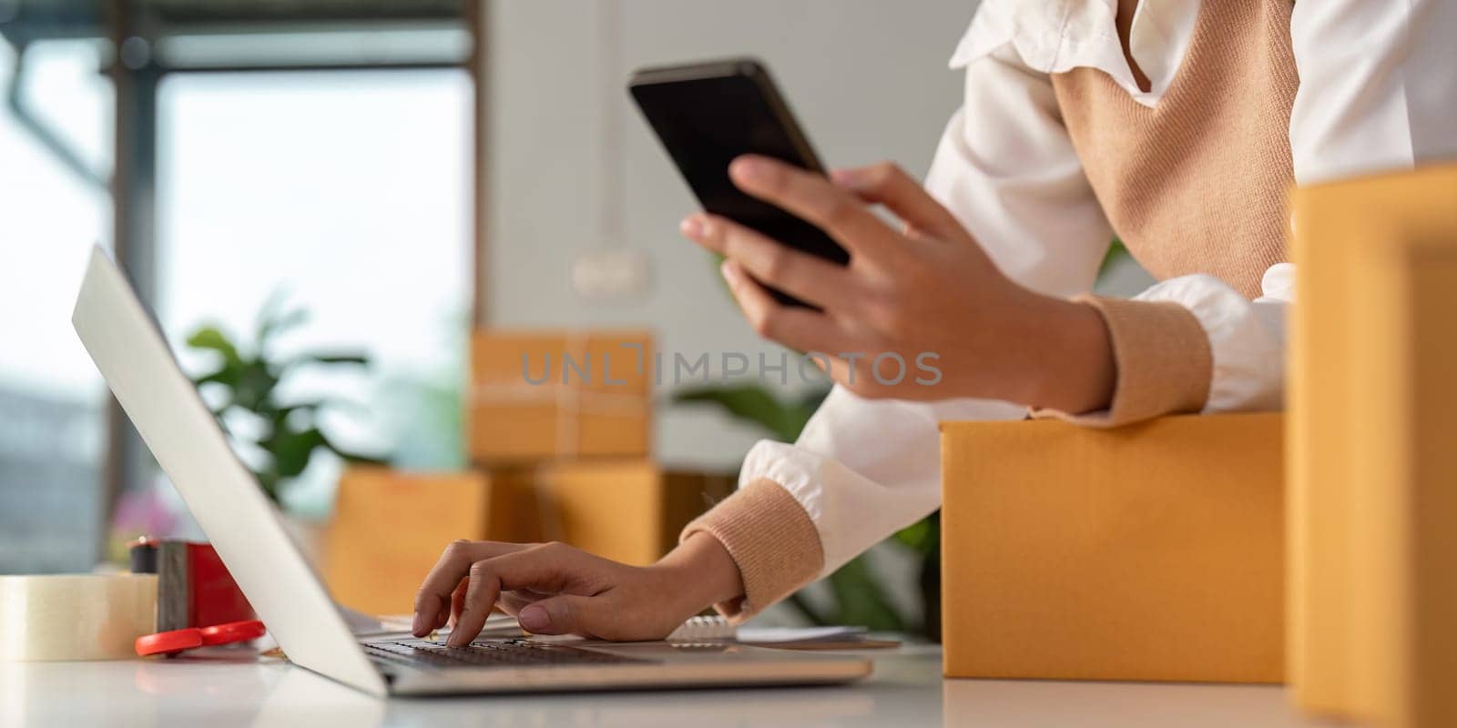 Woman entrepreneur prepare parcel box and check online order on laptop computer for commercial checking delivery. online marketing, packing box, SME seller. startup business concept.