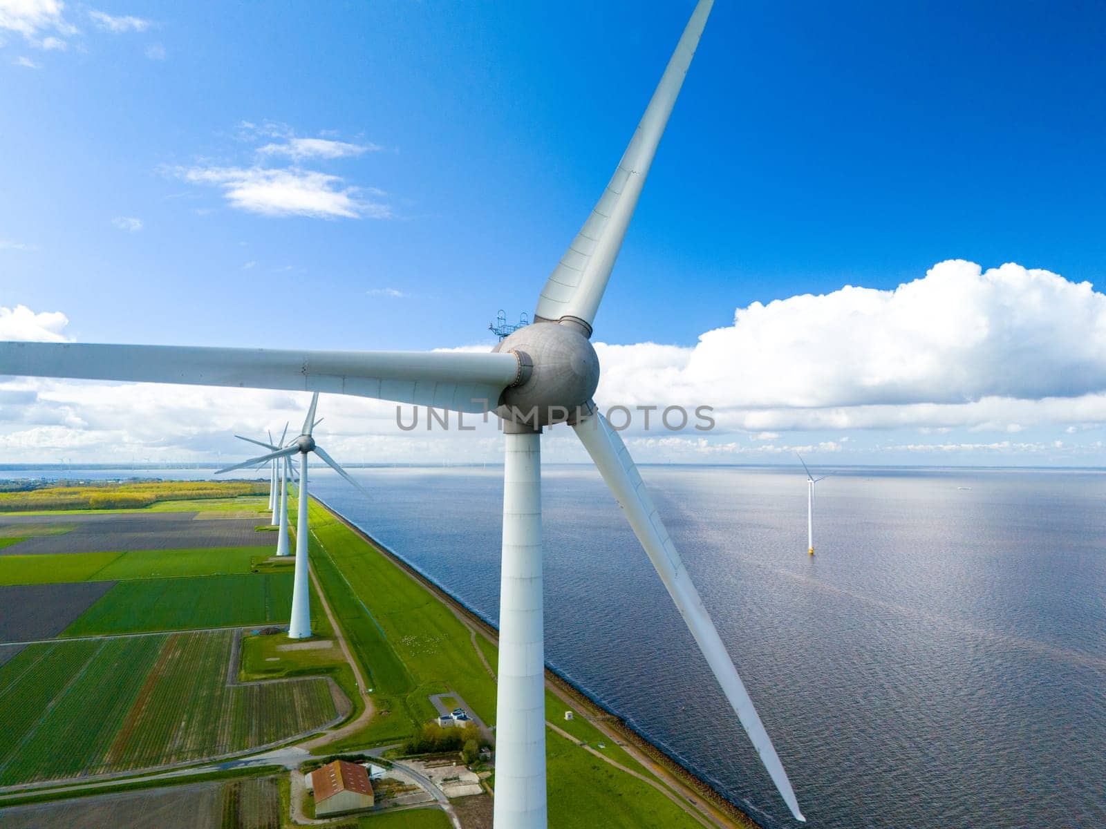 Rows of wind turbines stretch out towards the ocean, harnessing the power of the breeze to generate clean energy in harmony with the coastal landscape in the Noordoostpolder Netherlands