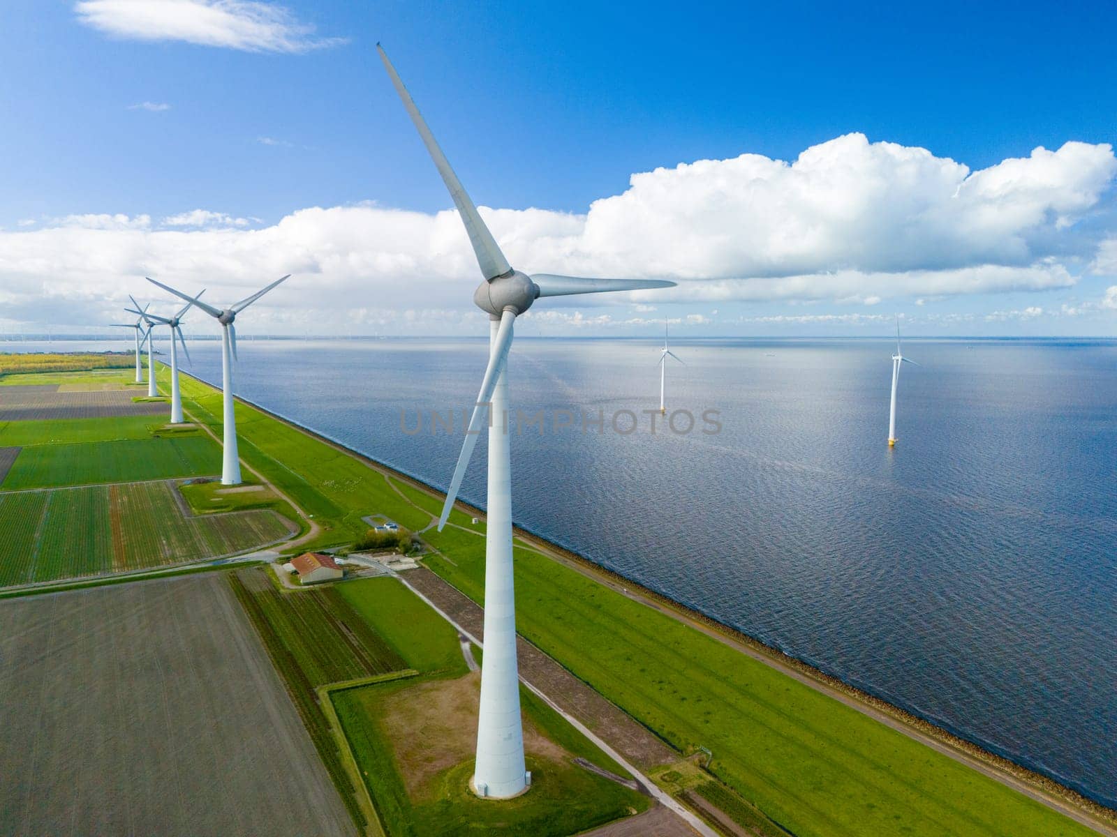 Serene wind farm with sleek turbines dancing gracefully near the ocean in the Netherlands on a clear Spring day.