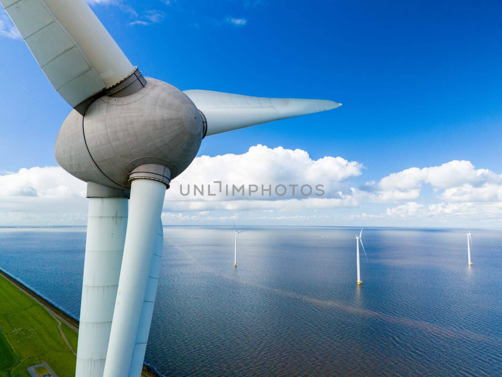 An aerial perspective captures the graceful movement of a wind turbine standing tall in the vast expanse of the ocean by fokkebok