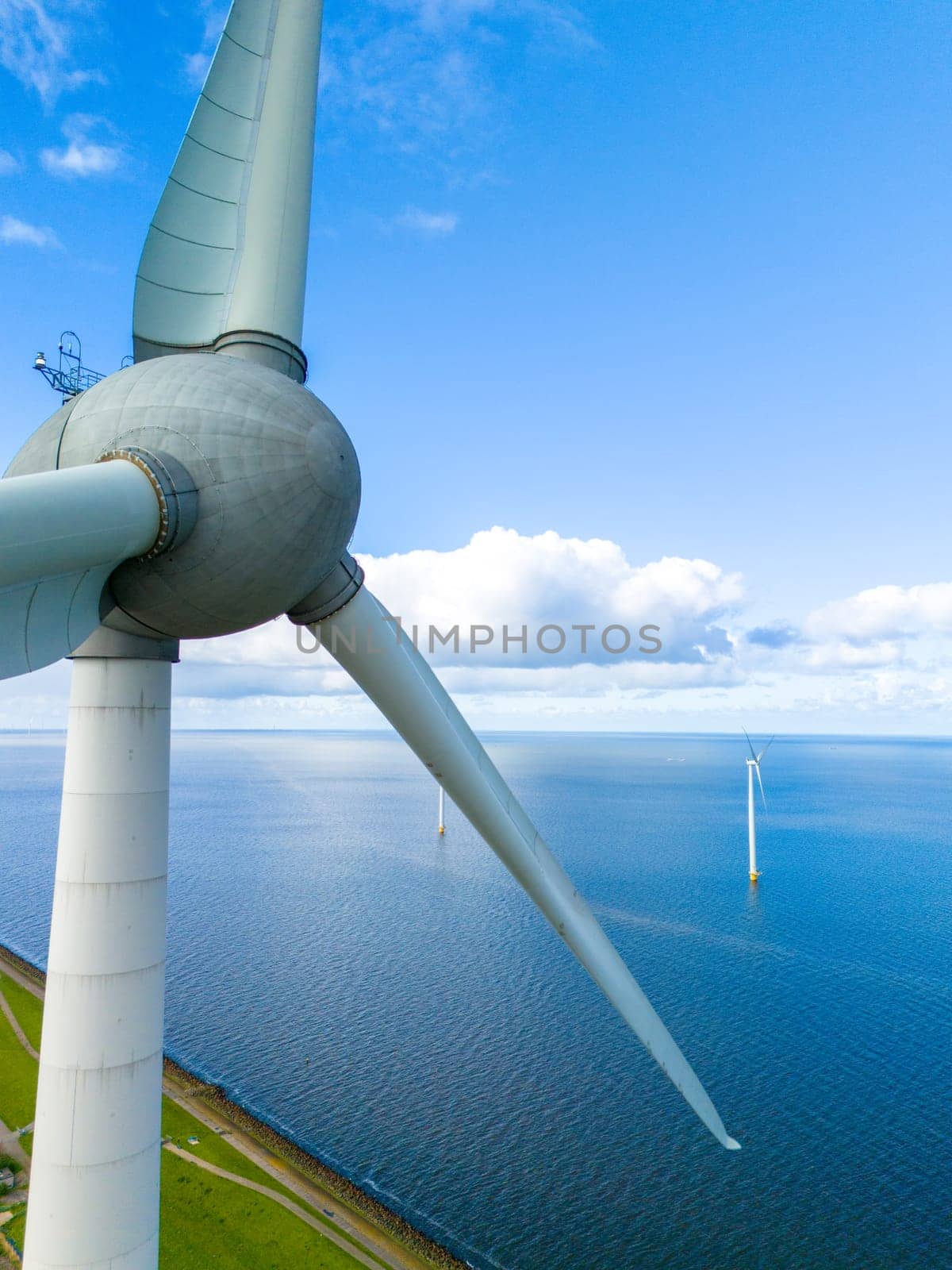 A lone wind turbine gracefully spins in the middle of a vast body of water, harnessing the winds energy in a picturesque setting in the Netherlands in Spring. windmill turbines in ocean