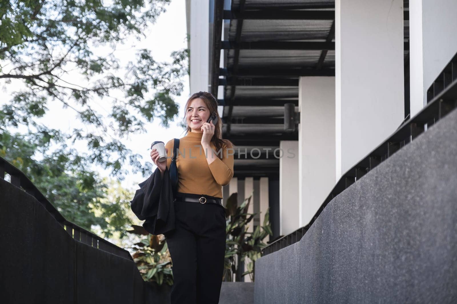 A woman is talking on her cell phone while walking down a stairway by wichayada