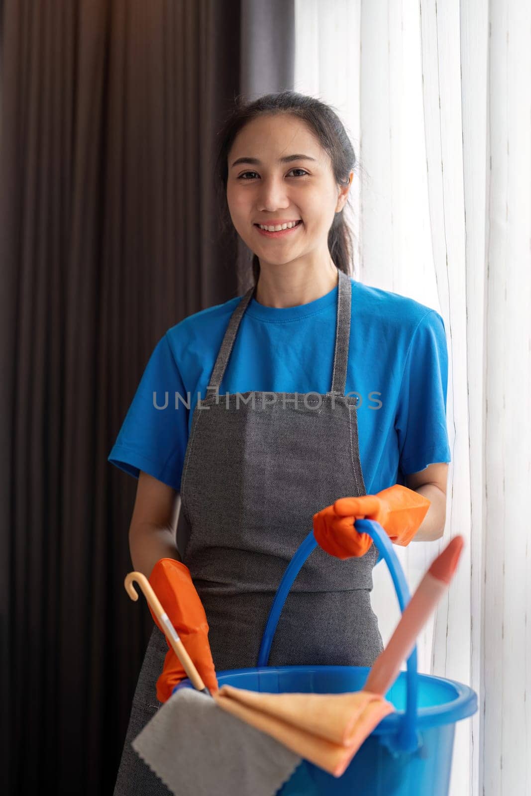 Cleaning product, and basket with woman asian staff cleaning service in bedroom to clean bacteria at apartment. cleaner or maid with container to work in room by nateemee