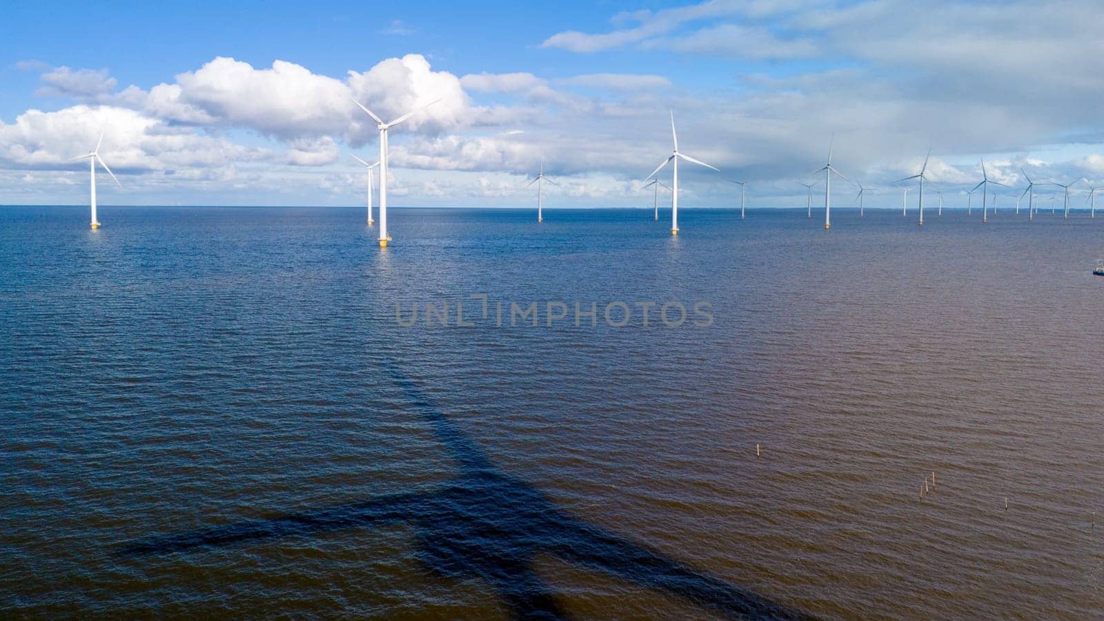 A picturesque scene of a large body of water with numerous windmills in the background, creating a harmonious blend of man-made structures and natural elements. windmill turbines in ocean Netherlands