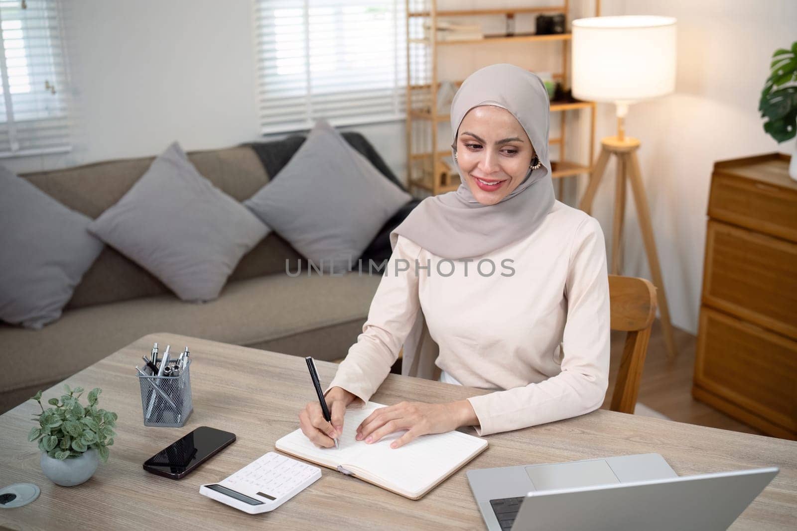 Young muslim business woman calculate budget money finance. Muslim woman accountant use calculator typing laptop counting tax loan bills online payment write document paperwork at home office.