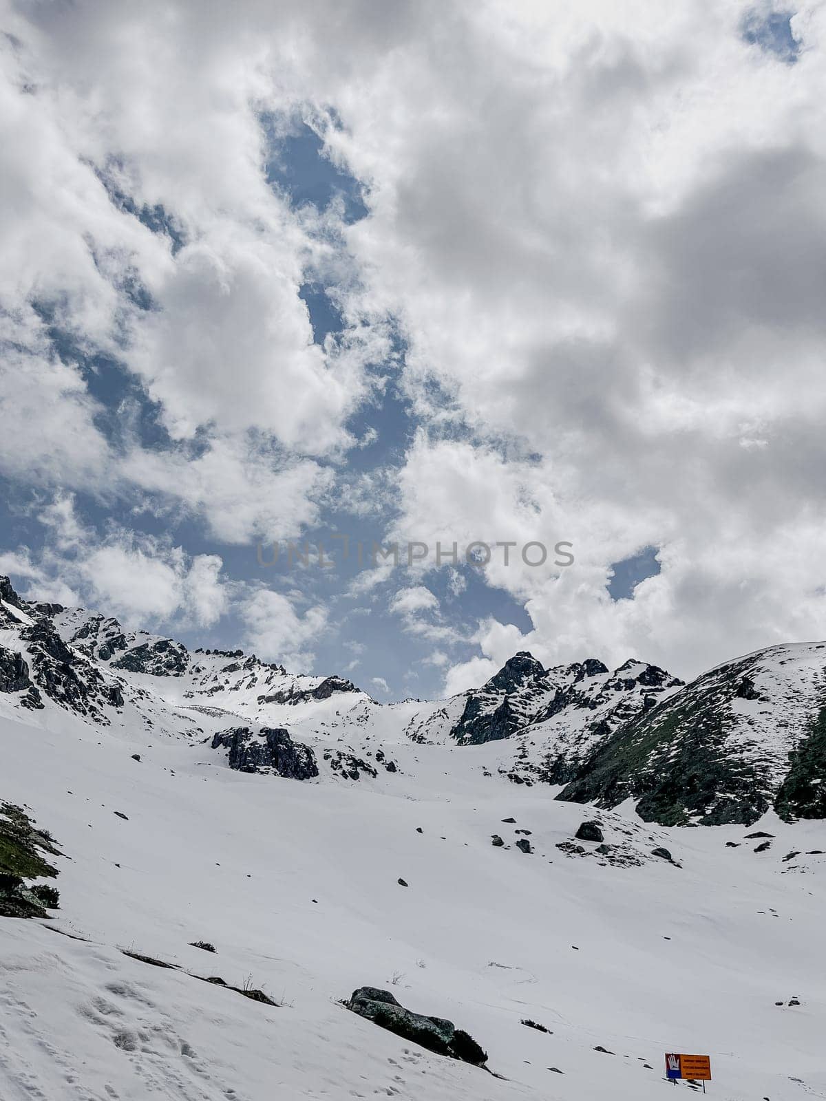 Snowy mountain landscape with blue sky and clouds for travel or tourism brochure by Pukhovskiy