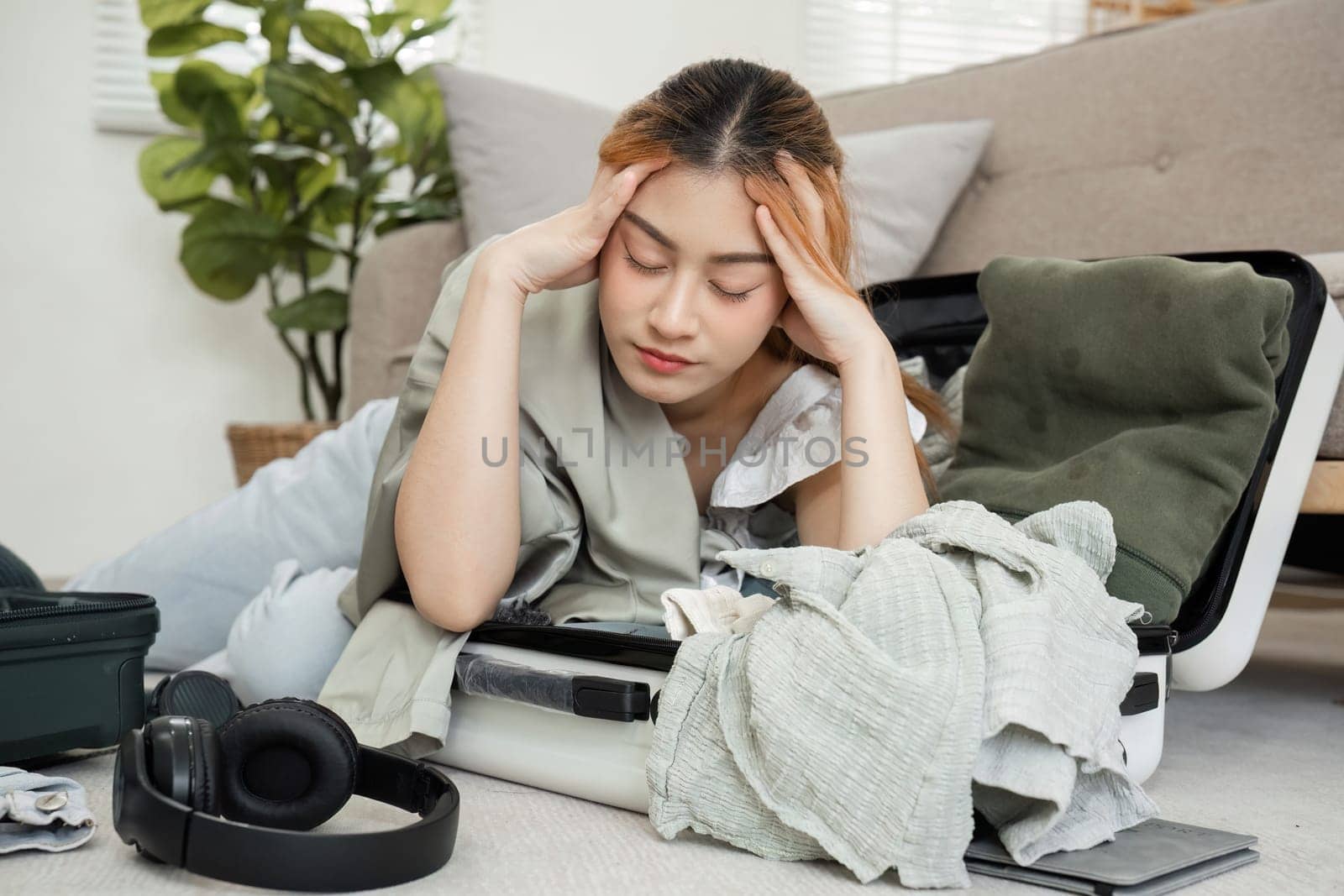 Asian female tourist is tired from packing her suitcase, checking her belongings and passport in preparation for her weekend trip..