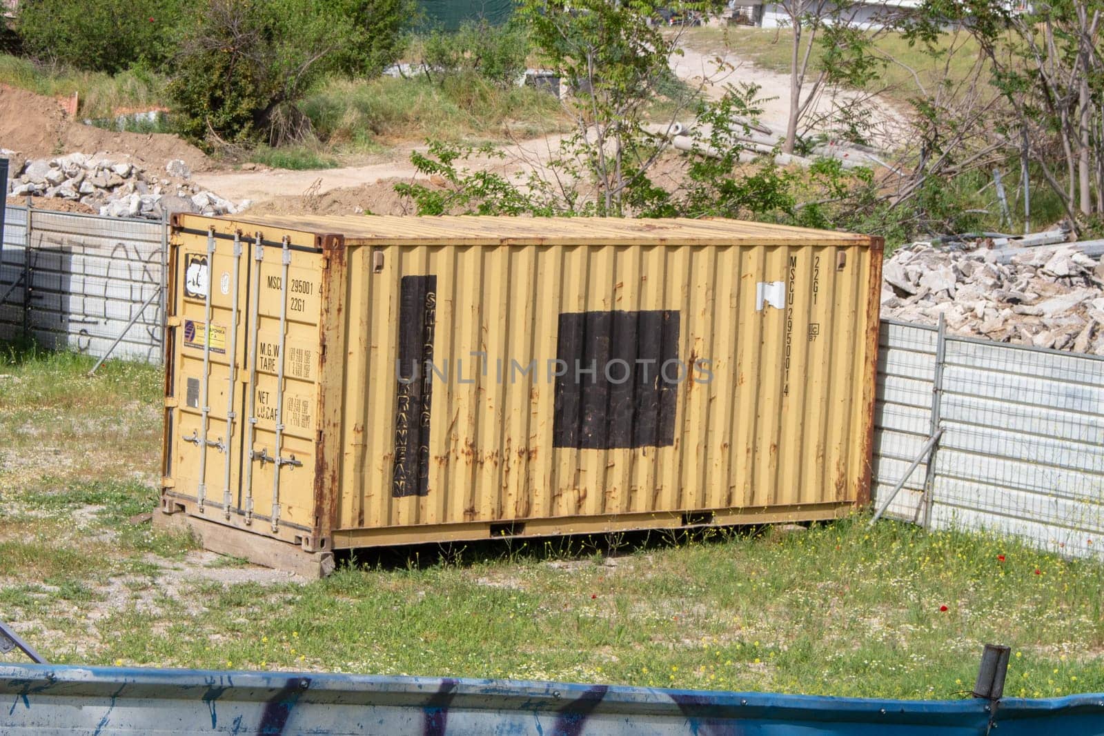 A shipping container nestled in a yard serves as a robust industrial storage solution, efficiently housing goods and materials in a commercial setting