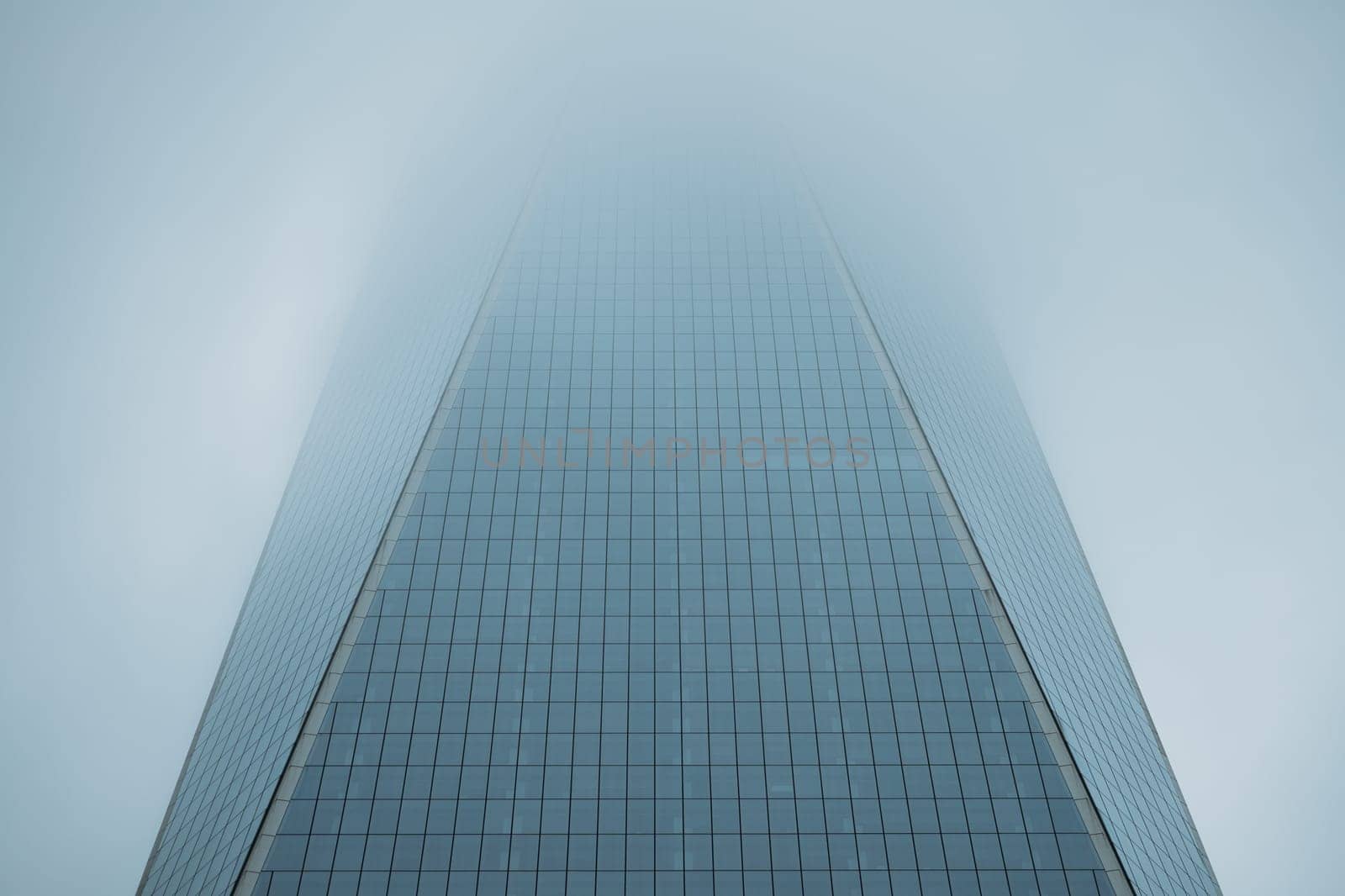 Vanishing Perspective of Modern Glass Skyscraper against Cloudy Sky by apavlin