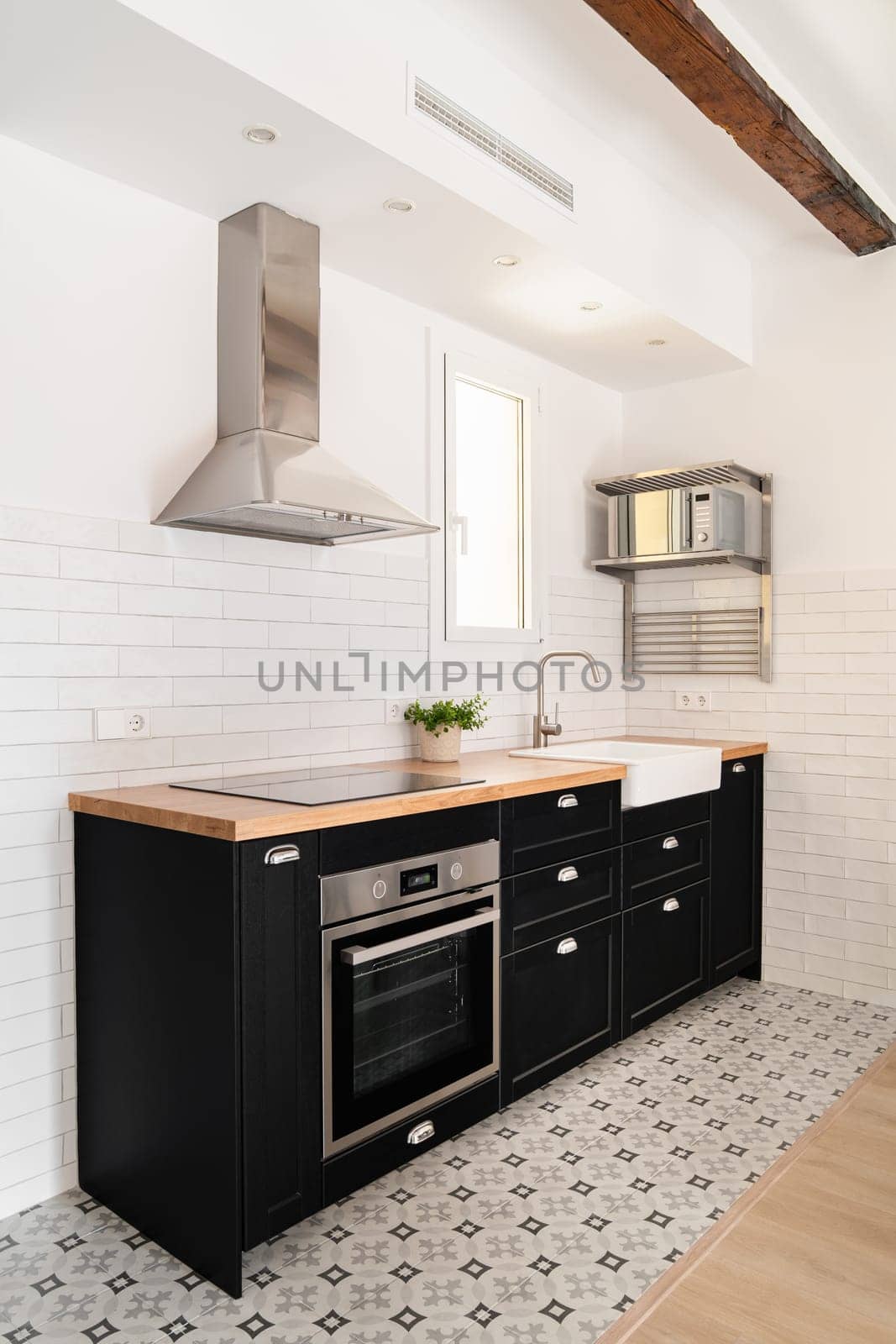 Vertical shot black kitchen island with drawers stove and convection cooker and modern appliances in scandinavian style apartment in new building. Copyspace.