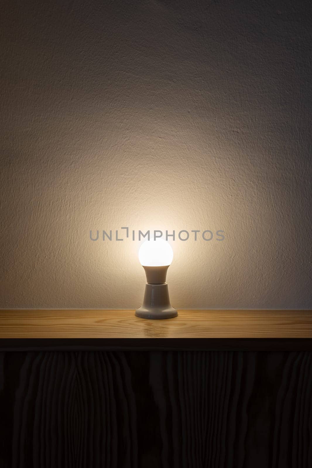 A Light Bulb On A Wooden Table by apavlin