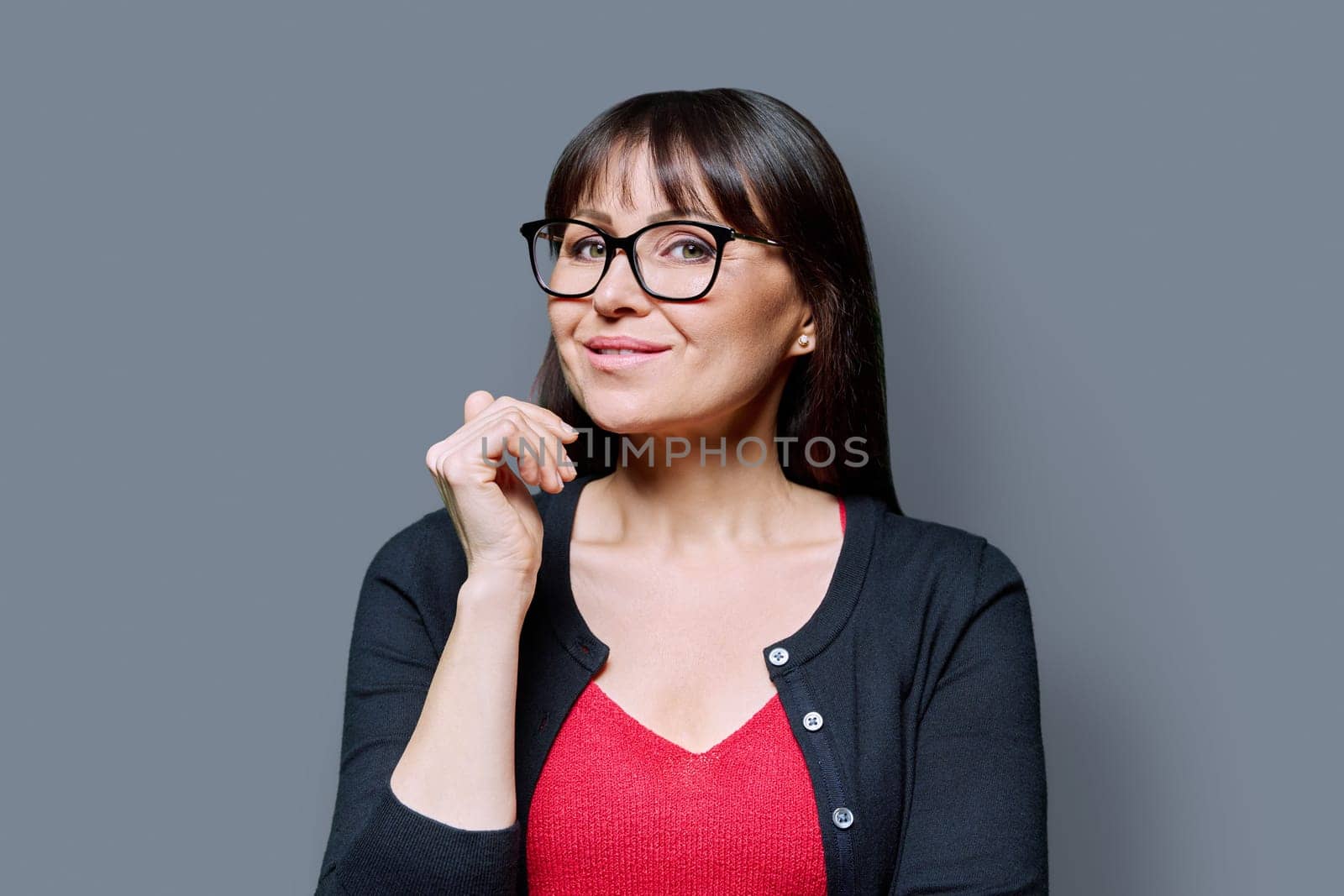 Headshot portrait of smiling with teeth mature woman on grey studio background. Successful elegant beautiful happy middle-aged female looking at camera. Beauty, health, lifestyle, 40s people