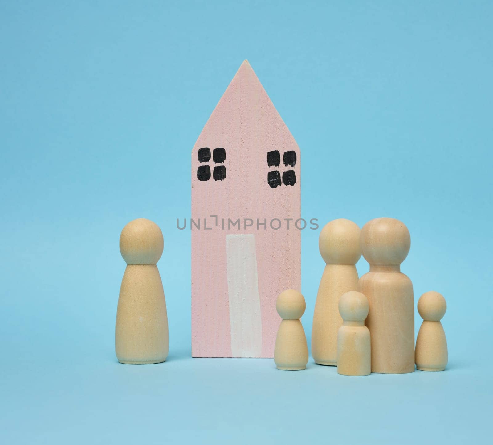 Wooden house and miniature figurines of a family on a blue background. The concept of selling and buying real estate by ndanko