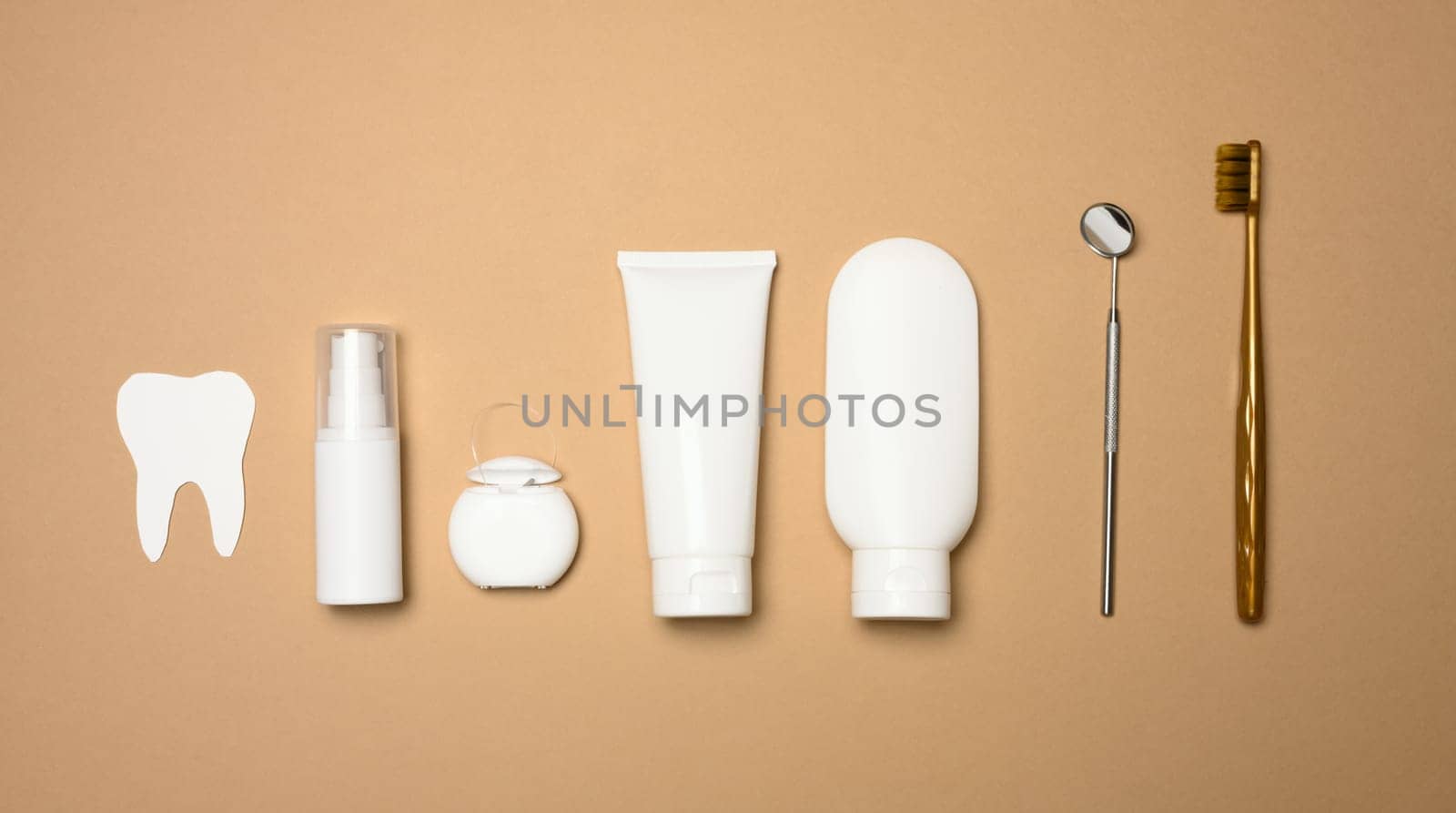 Toothbrush, toothpaste and paper tooth on a brown background, oral hygiene. View from above