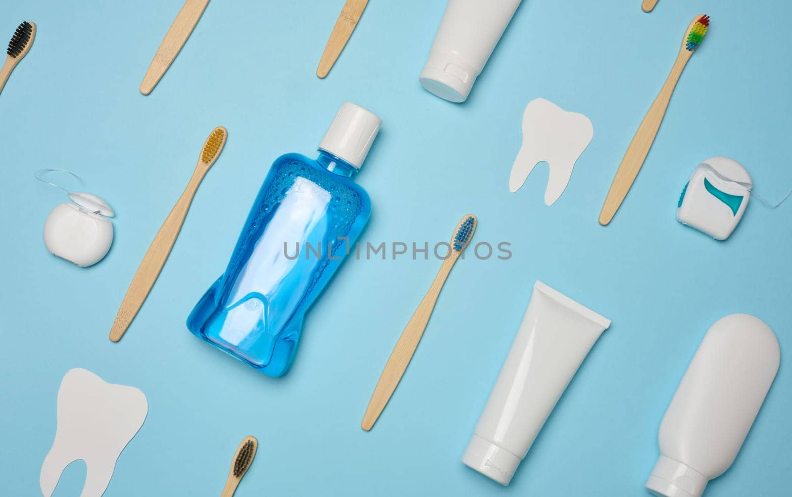 Mouthwash, toothpaste tube, dental floss on a blue background, oral hygiene.  Top view