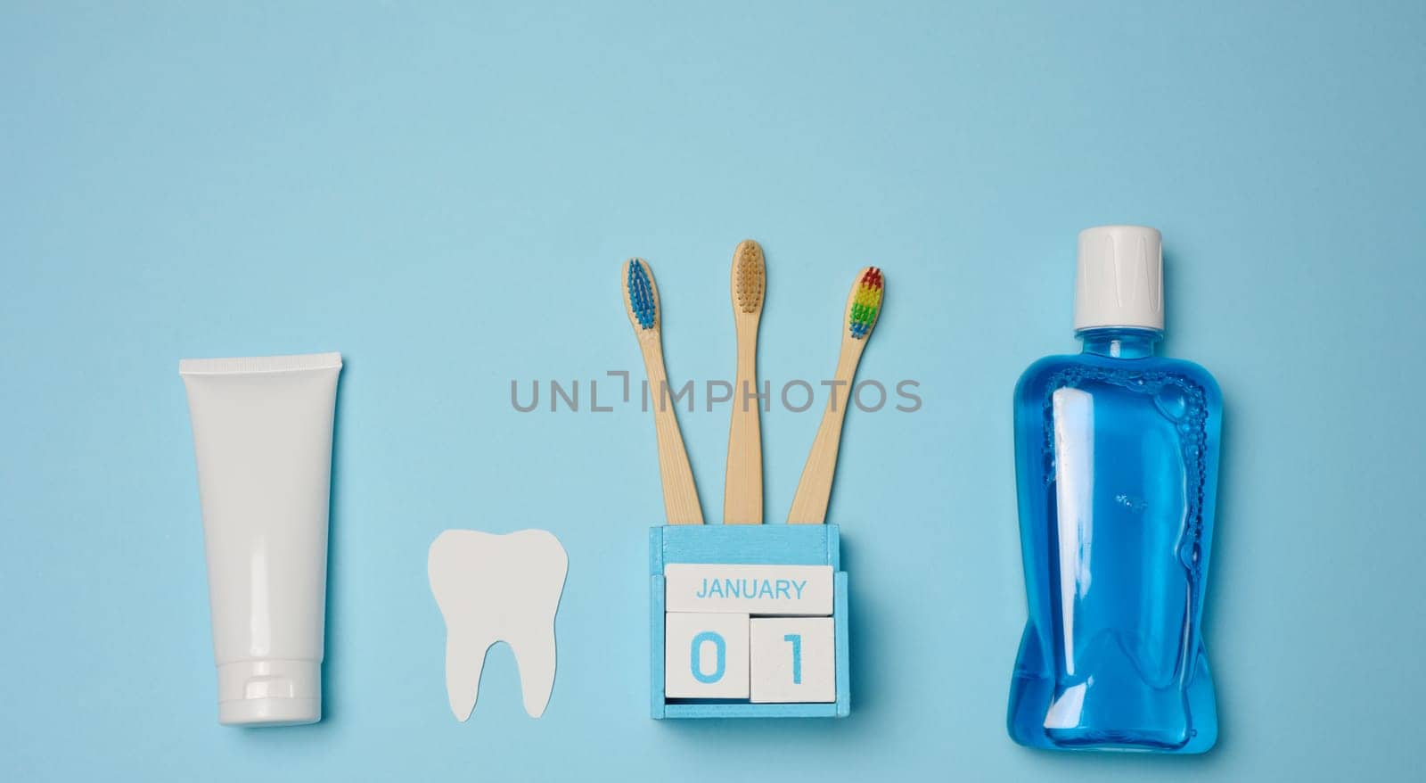 Mouthwash, toothpaste tube, dental floss on a blue background, oral hygiene. Top view