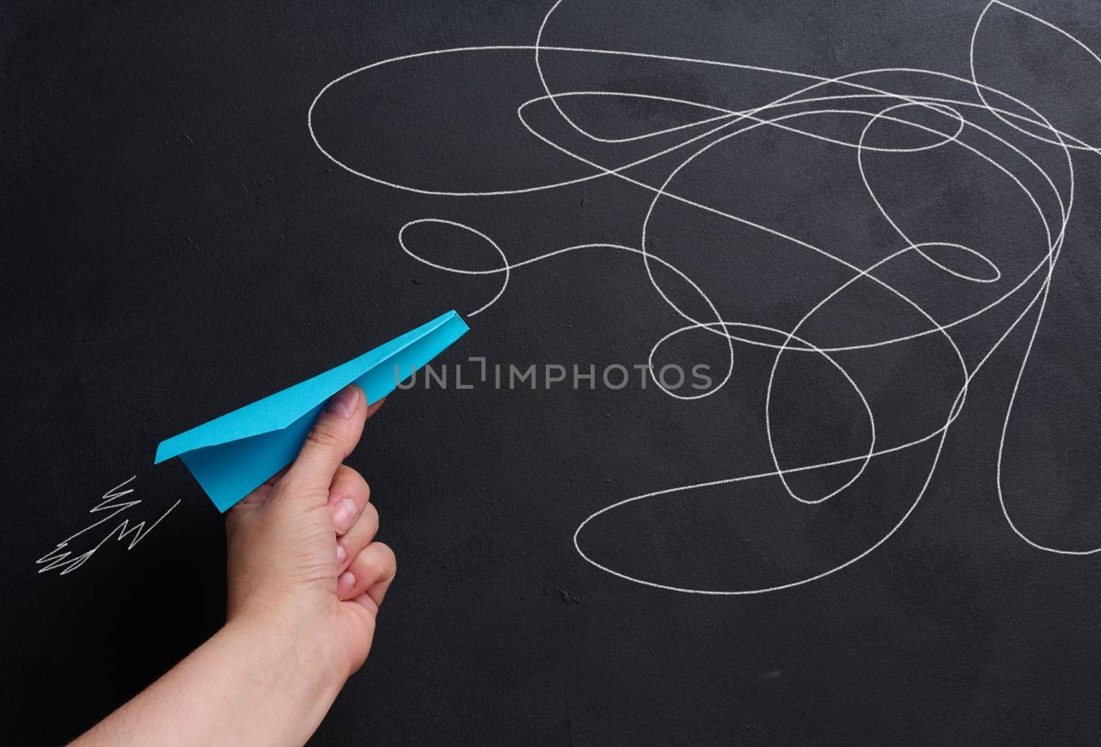A hand holds a paper airplane with a drawn flight trajectory on the board, representing the concept of support and mentorship by ndanko