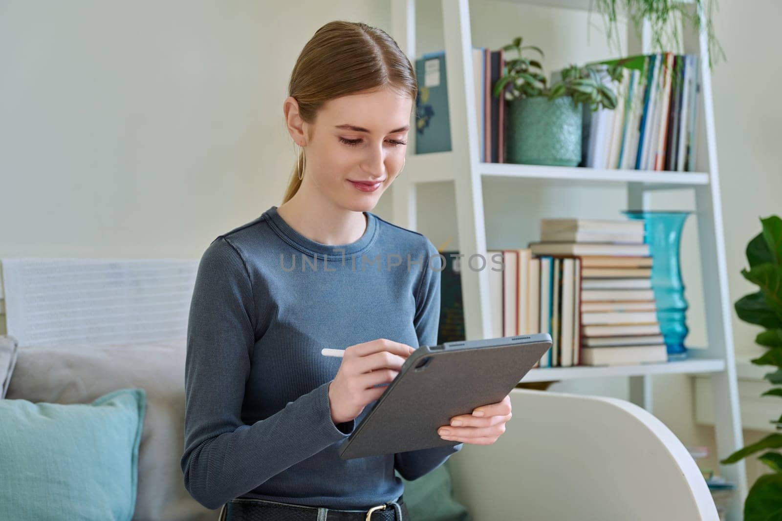 Young female teenager with digital tablet, stylus drawing illustrating sitting at home by VH-studio