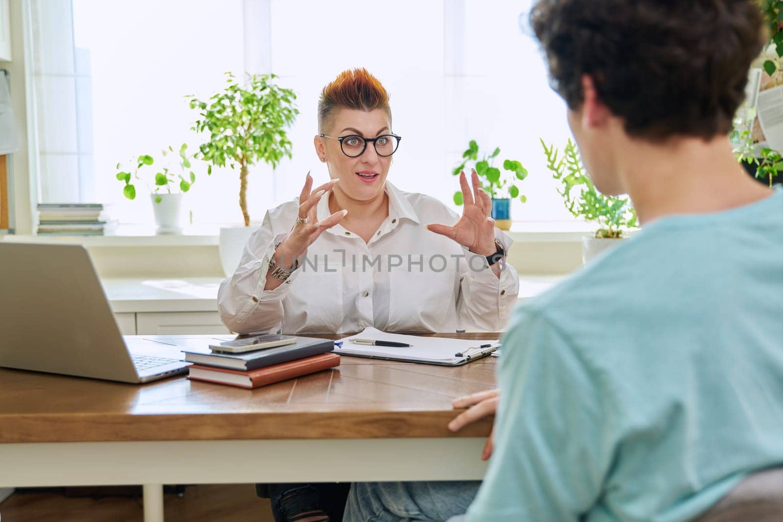 Female professional psychologist, mental therapist talking with young man in office by VH-studio