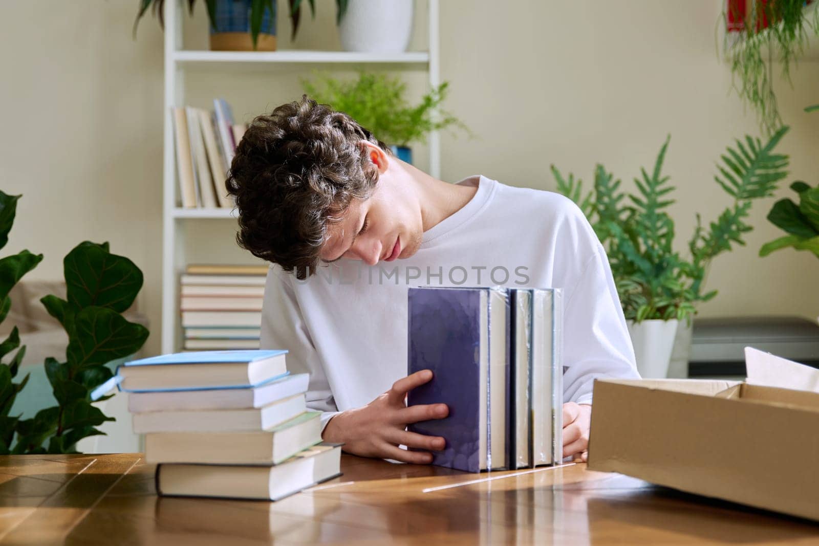 Satisfied young male customer unpacking cardboard box with online purchases, new books by VH-studio