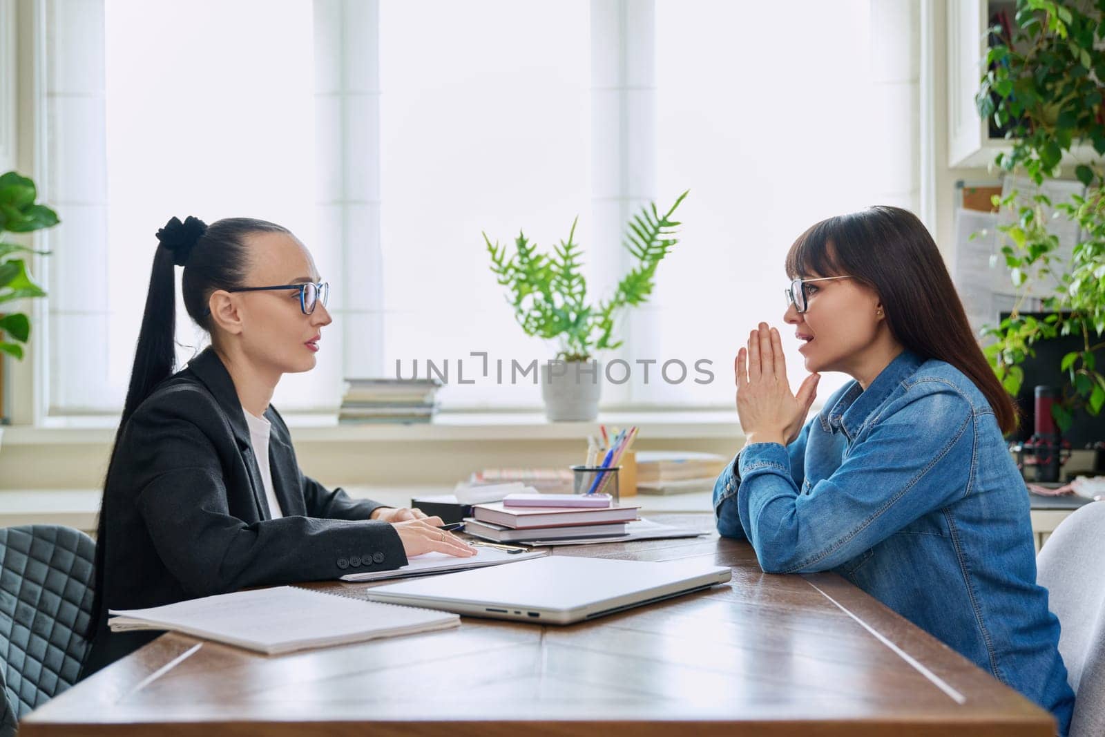 Mental therapy session of mature female with professional psychologist counselor. Talking serious women sitting at table, psychology, psychotherapy, counseling, social service, support help treatment