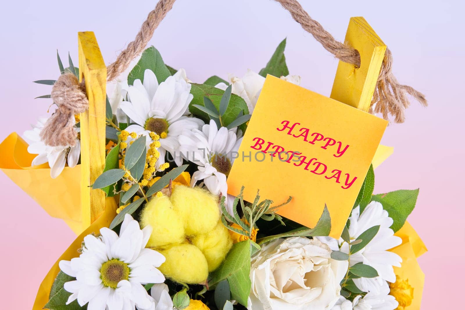 The concept of birthdays and holidays. Happy Birthday phrase on a yellow sticker in a bouquet of flowers